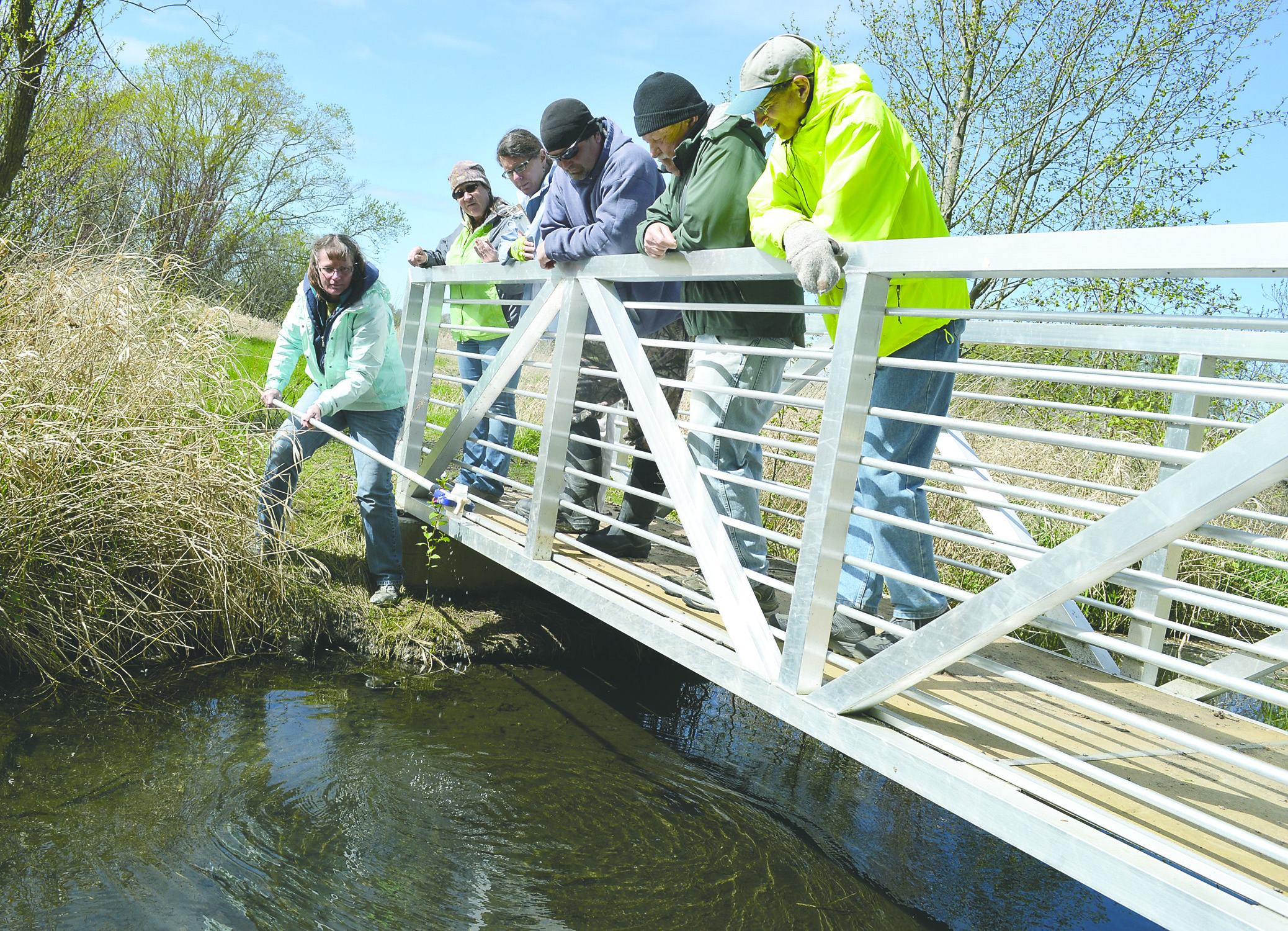 Sue Waldrip grabs a sample from Meadowbrook Creek while fellow Streamkeepers Lori DeLorm