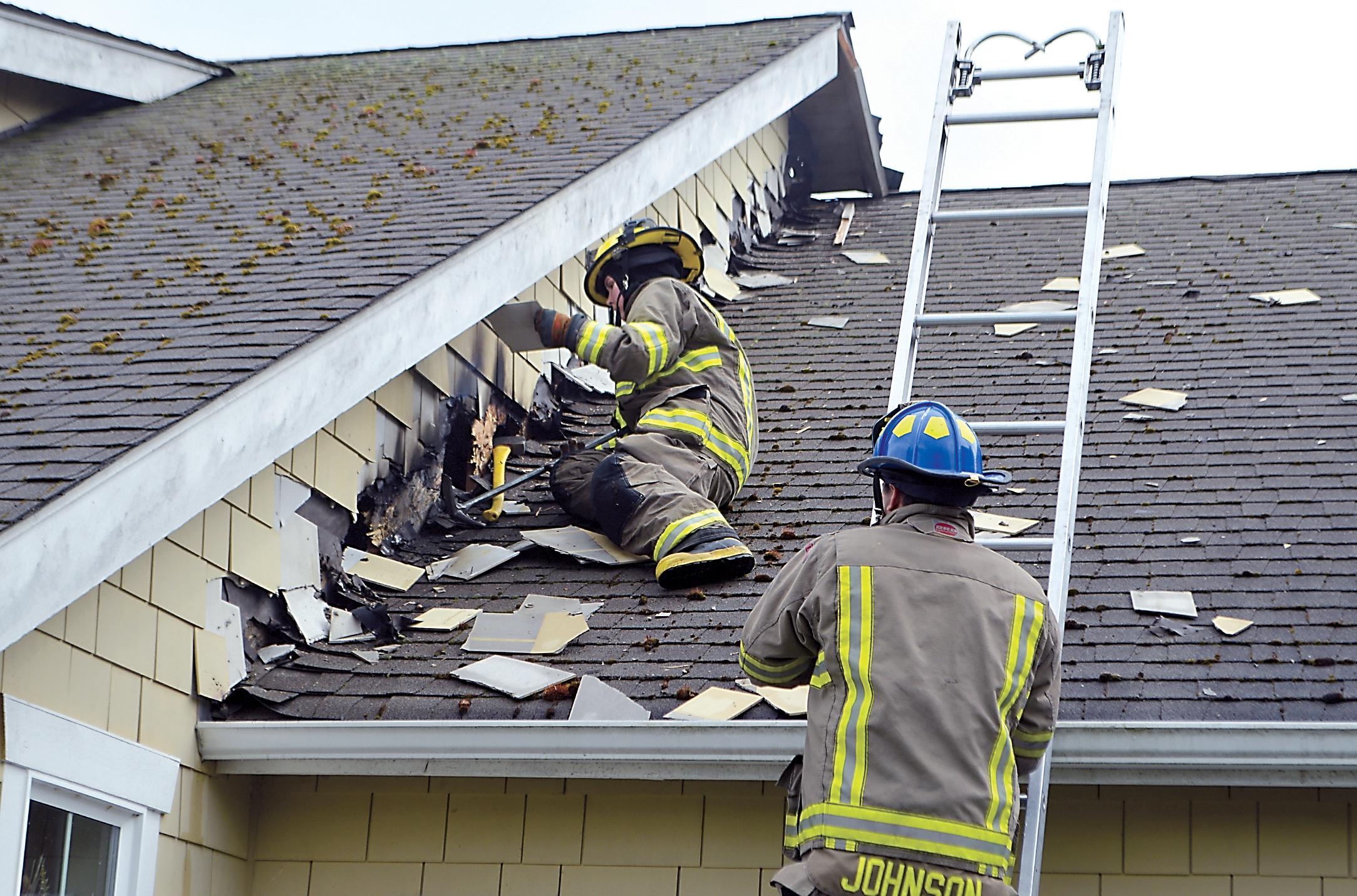 Clallam County Fire District 3 personnel inspect the roof of a home at 80 Craftsman Way in Sequim after a lightning bolt struck the unoccupied house this morning.