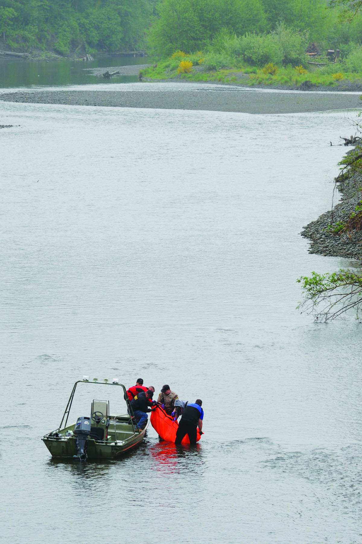 Officers get a body spotted near a boat ramp in the Quillayute River into a boat on Saturday afternoon. Lonnie Archibald/for Peninsula Daily News