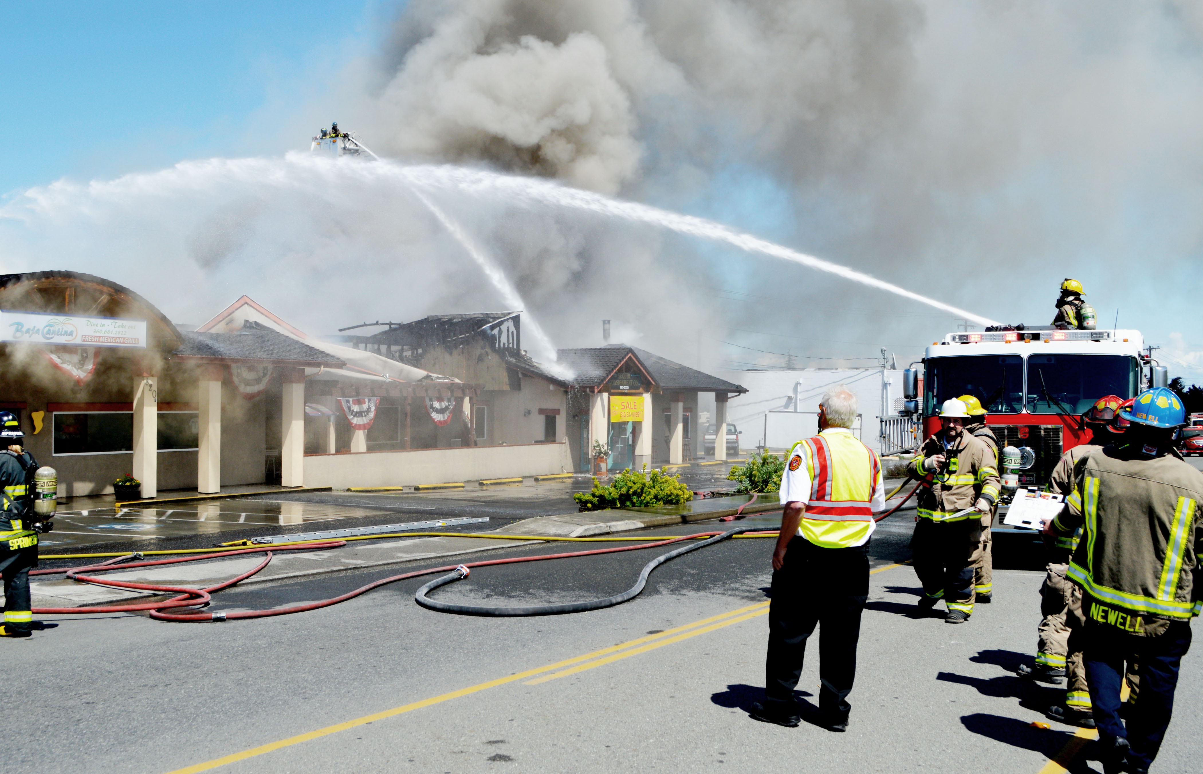 Firefighters from Clallam County Fire District No. 3 and Port Angeles train water on the building that housed Baja Cantina and Sequim Consignment on West Washington Street in Sequim today.  —Photo by Joe Smillie/Peninsula Daily News