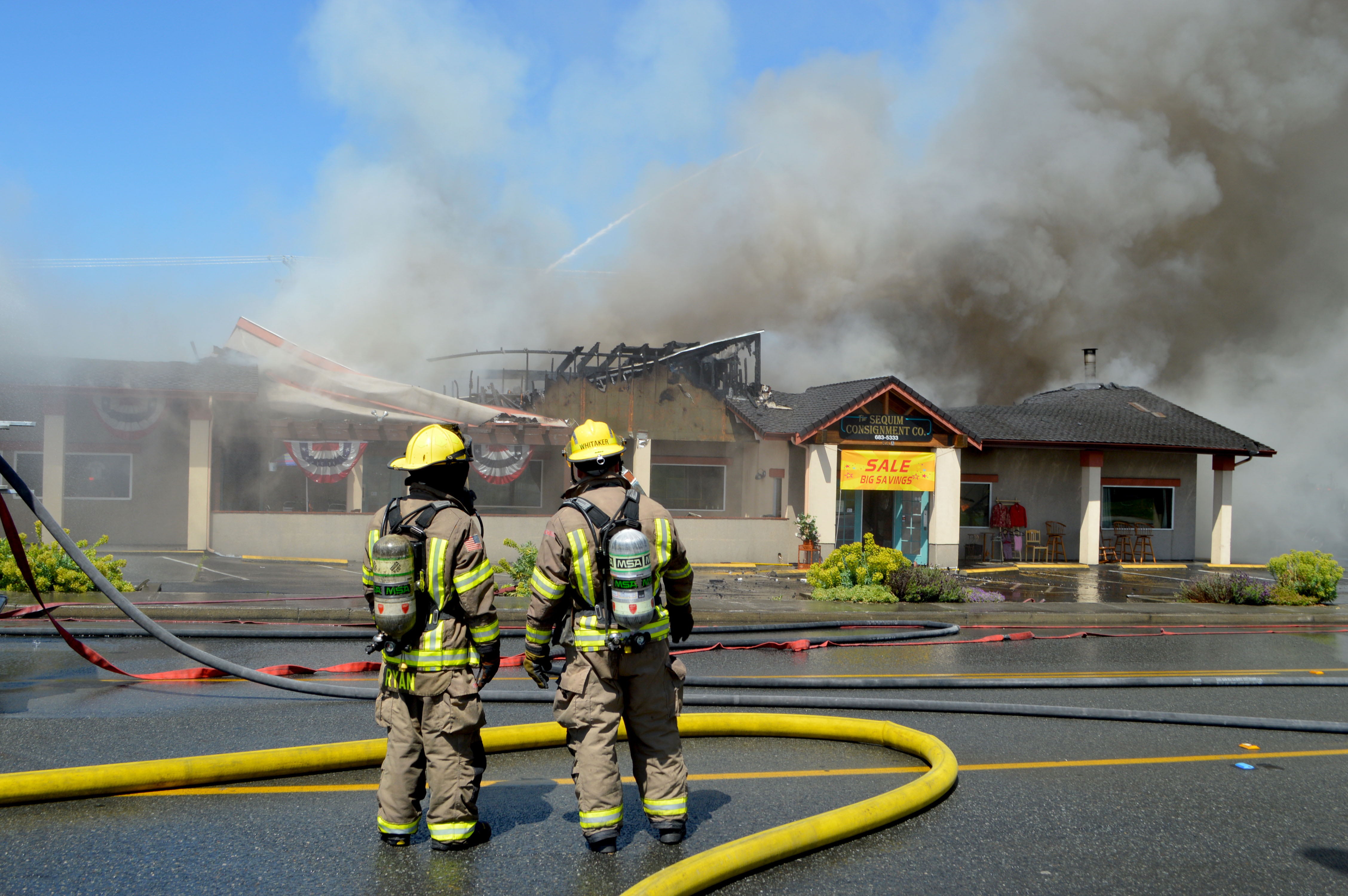 Firefighters view the remains of the building that housed Baja Cantina and Sequim Consignment on West Washington Street in Sequim late Monday afternoon.  —Photo by Joe Smillie/Peninsula Daily News