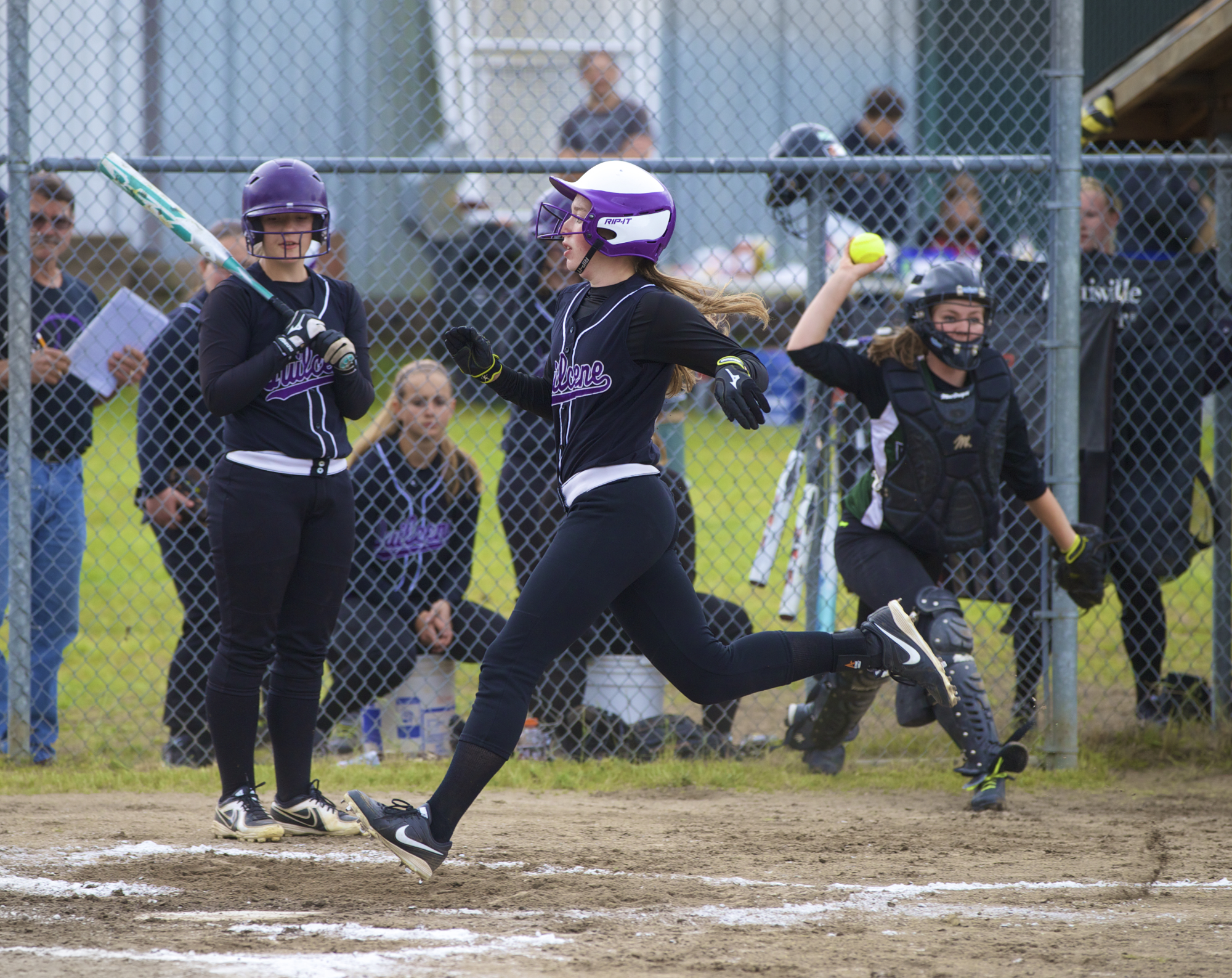 Quilcene's Megan Weller crosses home plate after a wild pitch as teammate Allison Jones