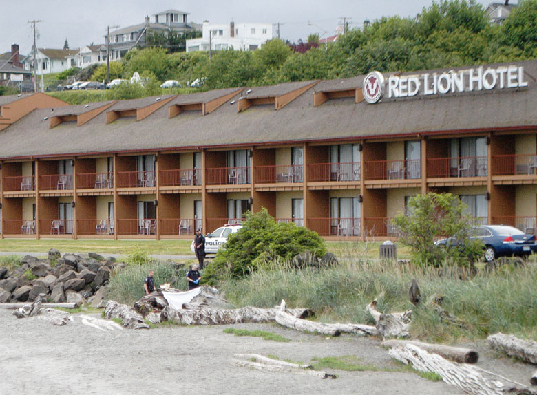 Port Angeles police investigate the scene where a body was found among riprap rock and driftwood at Hollywood Beach on Friday morning. Police closed the Waterfront Trail