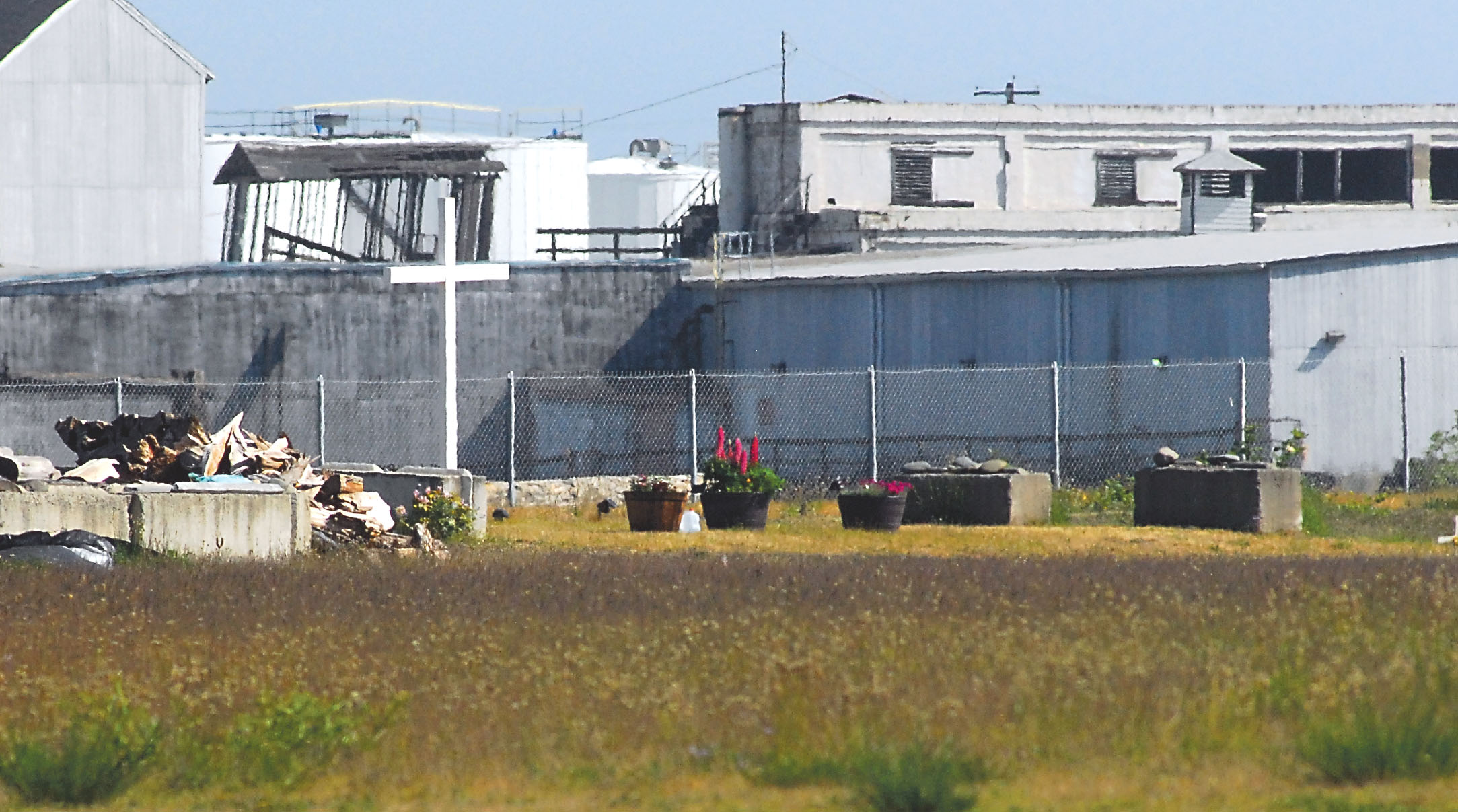 A white cross stands over the site of Tse-whit-zen in honor of tribal ancestors buried there. In the background are buildings of the Nippon Paper Industries USA mill. Keith Thorpe/Peninsula Daily News