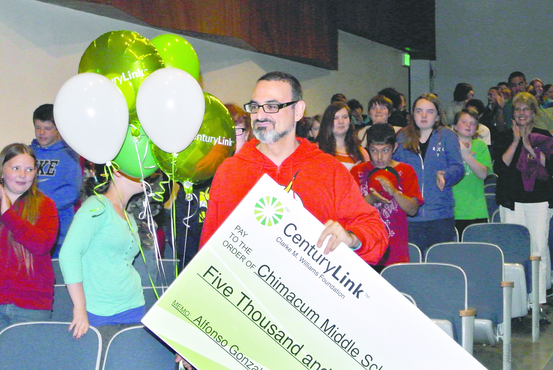 Chimacum Middle School teacher Alfredo Gonzalez receives a giant check at a surprise assembly held Thursday. Charlie Bermant/Peninsula Daily News