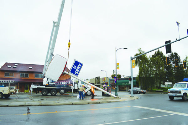 Workers with Admiralty Crane take a torch to the cross bar of the old Gull service station sign in downtown Sequim on Monday. Joe Smillie/Peninsula Daily News