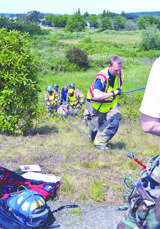 Rescue workers pull up an injured woman who drove her Toyota Land Cruiser down a 60-foot blackberry-covered hill off the Sequim Avenue exit off U.S. Highway 101 on Friday afternoon. Joe Smillie/Peninsula Daily News