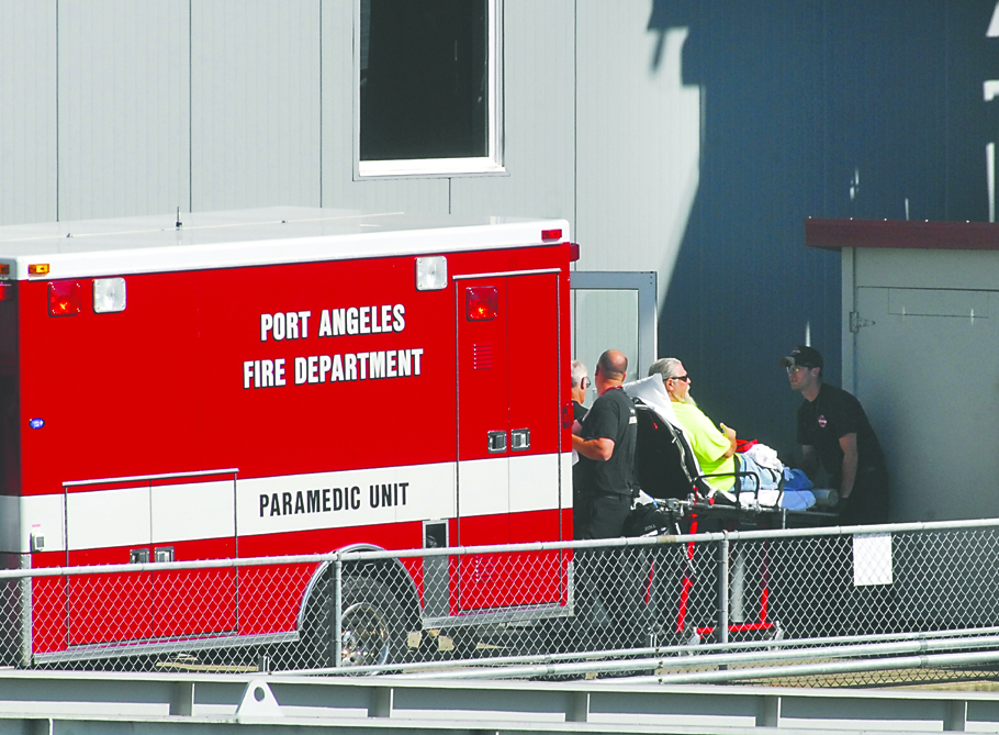 Emergency workers load an unidentified man into an ambulance in Port Angeles on Friday. Keith Thorpe/Peninsula Daily News