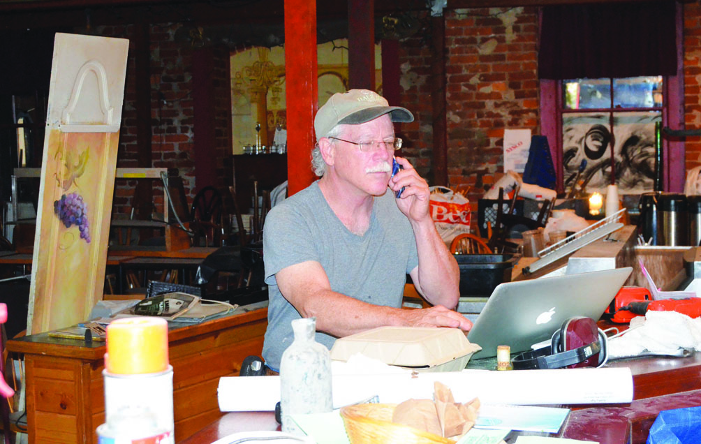 Mark Cole checks messages via computer and phone during the Upstage remodeling in Port Townsend recently. Charlie Bermant/Peninsula Daily News