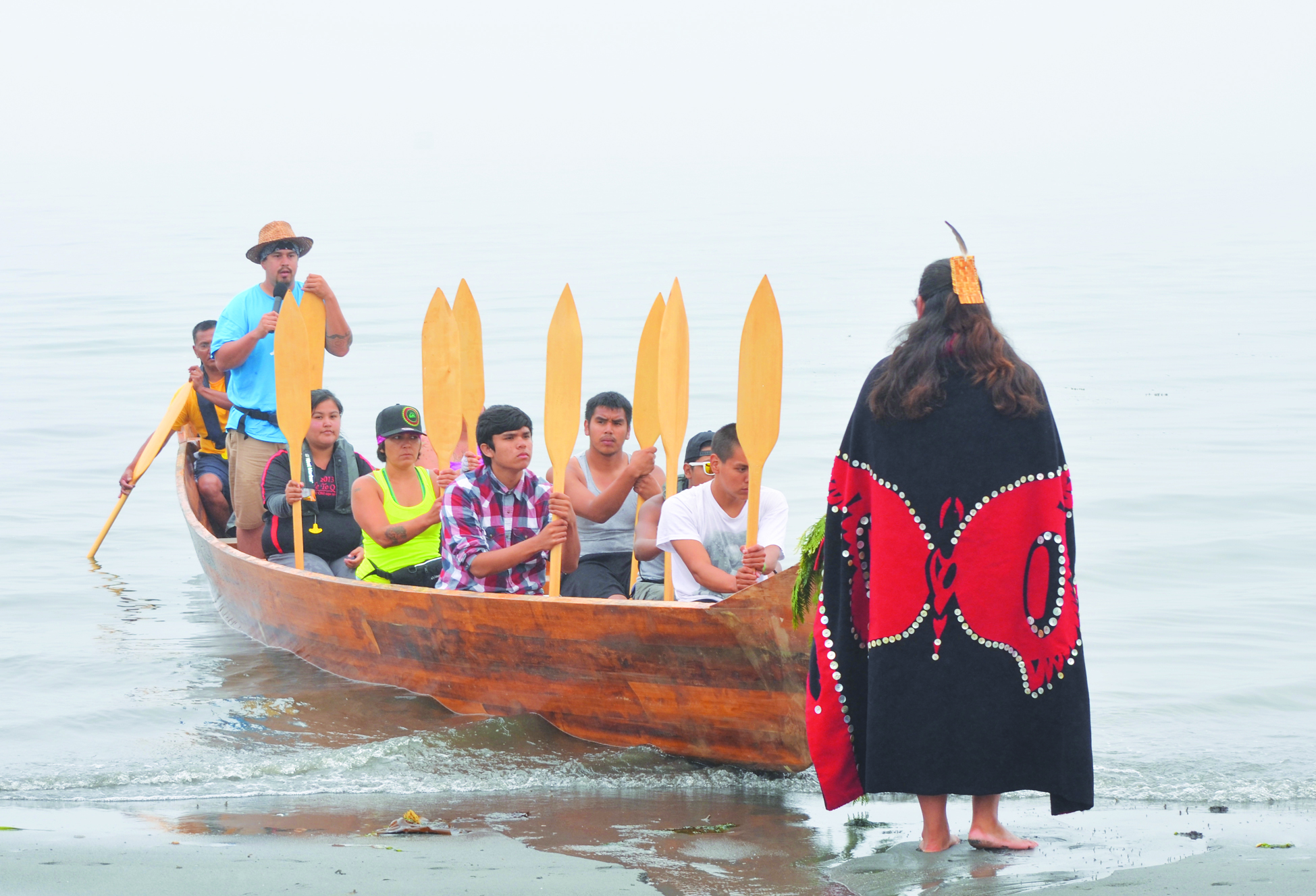 A Lummi tribal canoe is the first to arrive Sunday morning at Fort Worden State Park. It is greeted by Maurice Charles of the Lower Elwha tribe. Charlie Bermant/Peninsula Daily News