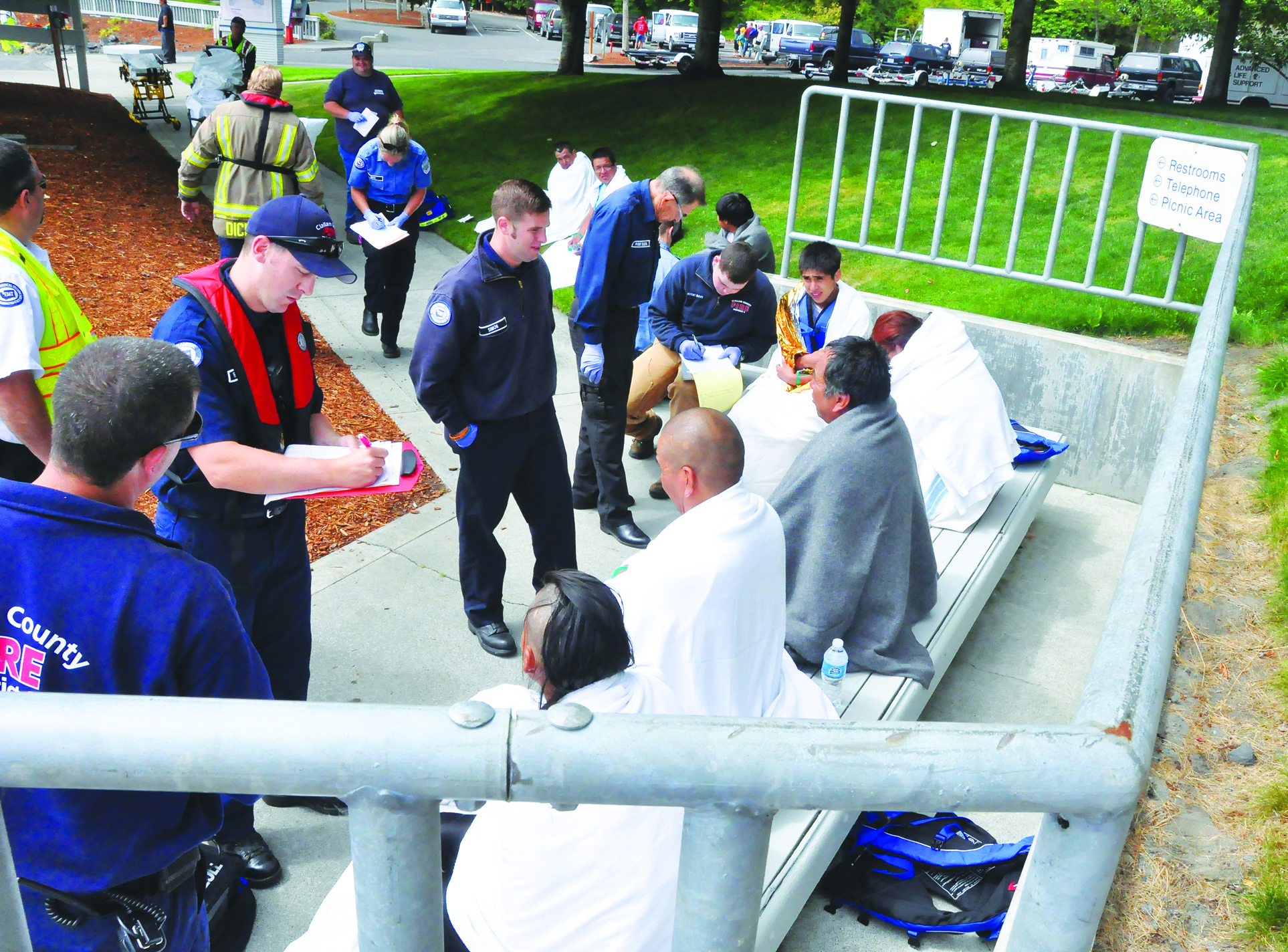 Clallam County Fire District No. 3 and Olympic Ambulance personnel evaluate eight tribal members at John Wayne Marina in Sequim on Monday. Jay Cline/Sequim Gazette