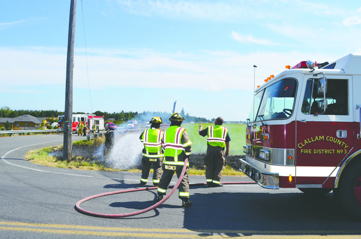 Firefighters work at the corner of Kitchen-Dick Road and Woodcock Road west of Sequim to put out a small grass fire. Patrick Young/Clallam County Fire District No. 3