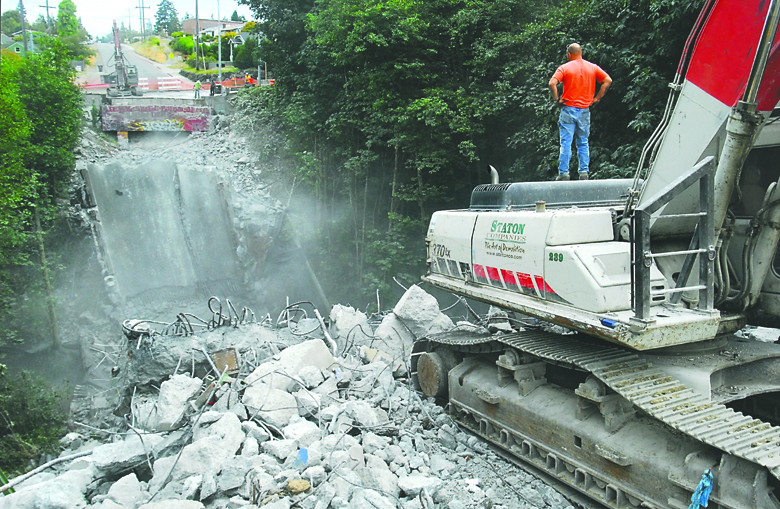 Equipment operator Dennis Steckler of Staton Cos. demolition looks over the remains of the Lauridsen Boulevard bridge over Peabody Creek in Port Angeles on Wednesday shortly after the bridge deck was dropped into the creek below. Keith Thorpe/Peninsula Daily News