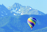 A balloon soars before the Olympic Mountain Range during the Sequim Balloon Festival