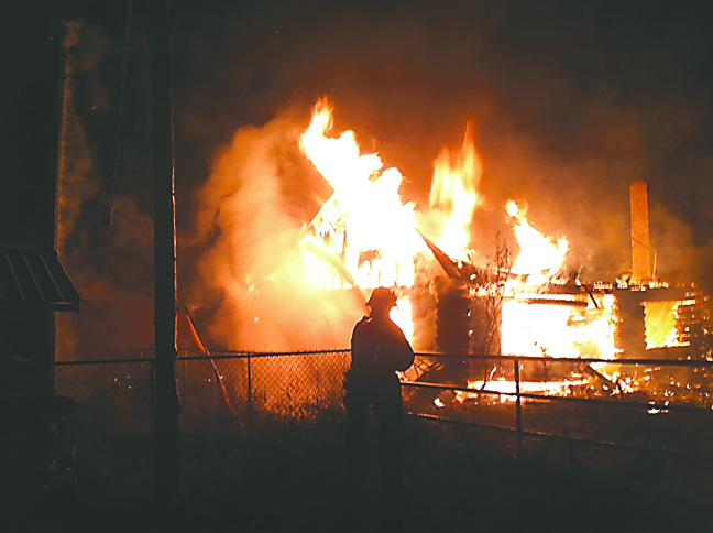 A log cabin west of the Elwha River burns in an early morning fire Tuesday. Clallam County Fire District No. 2