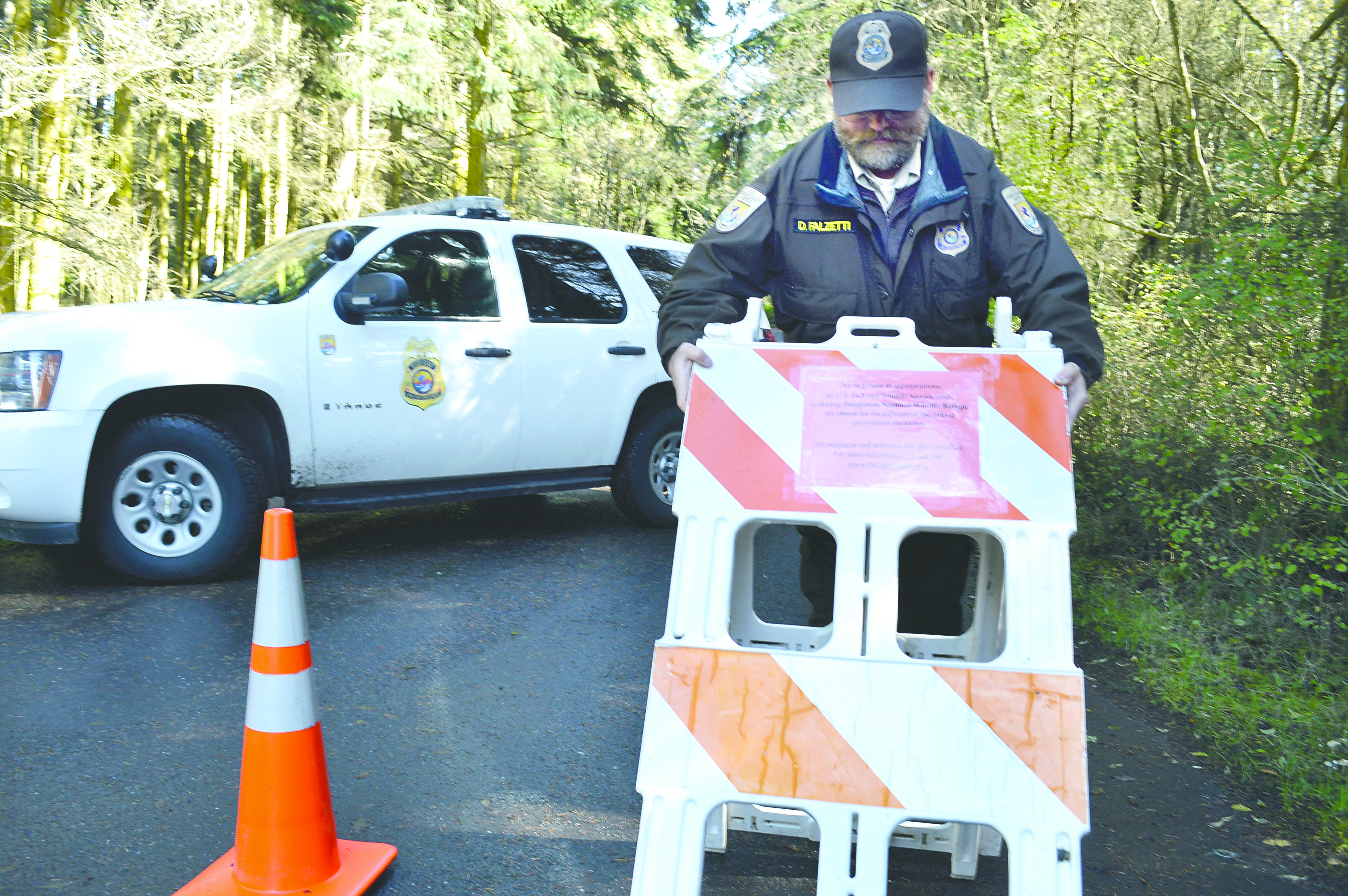 Federal wildlife officer Dave Falzetti sets out a barricade at the entrance to Dungeness National Wildlife Refuge after it was closed Tuesday. Joe Smillie/Peninsula Daily News