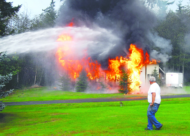 Homeowner Cliff Smith walks past a fully engulfed outbuilding containing a recreational vehicle at 3249 S. Regent St. in Port Angeles on Wednesday afternoon. Keith Thorpe/Peninsula Daily News