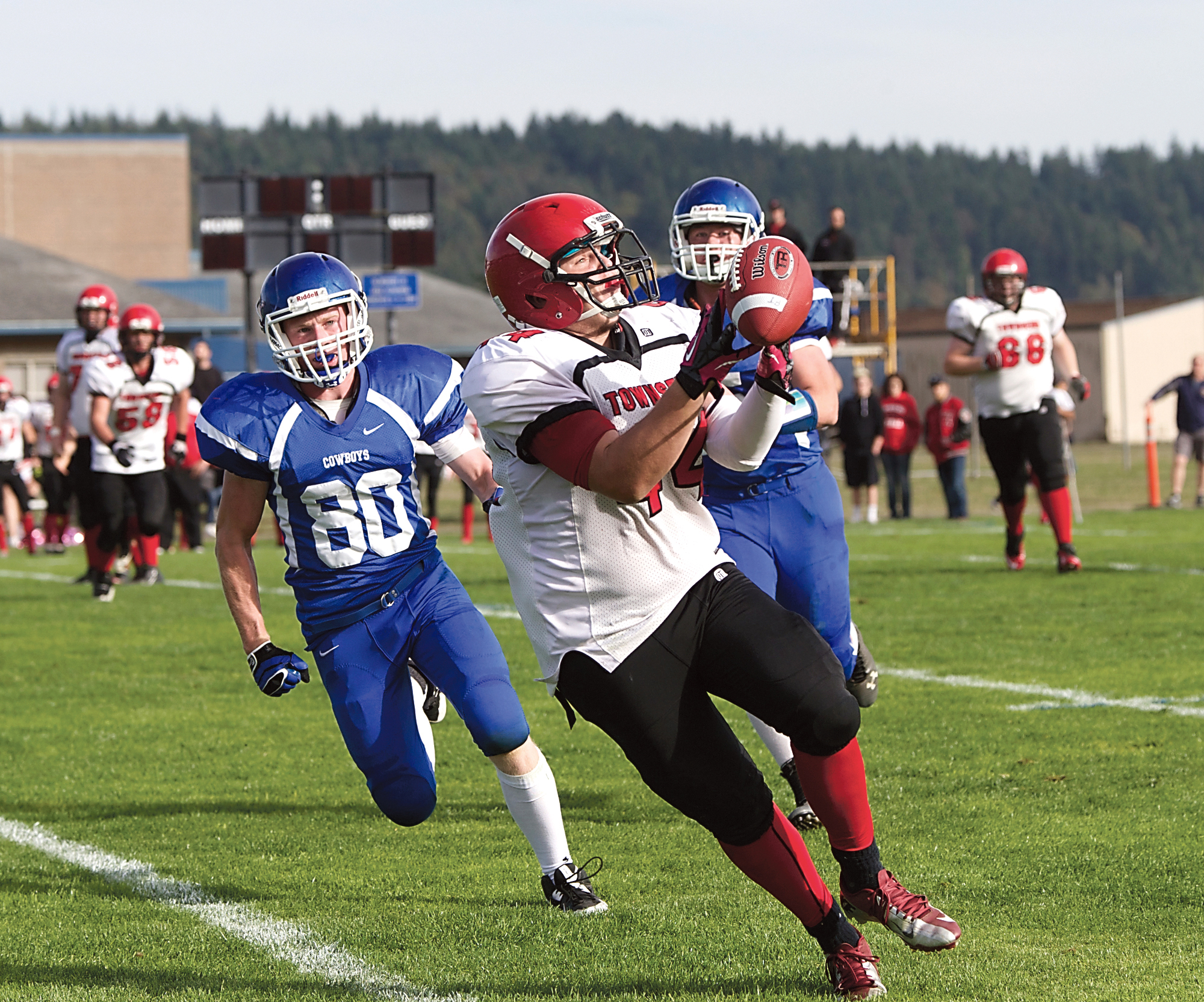 Port Townsend's Wesley Wheeler catches the ball on his fingertips for a 24-yard gain as Chimacum's Colton Shaw (80) and Lane Dotson