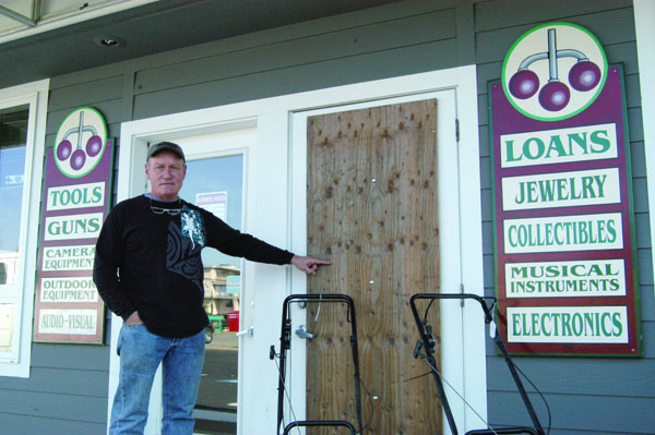 Angeles Pawn owner Ron Diimmel points to plywood that covers a door through which burglaries entered the store Oct. 1. Jeremy Schwartz/Peninsula Daily News