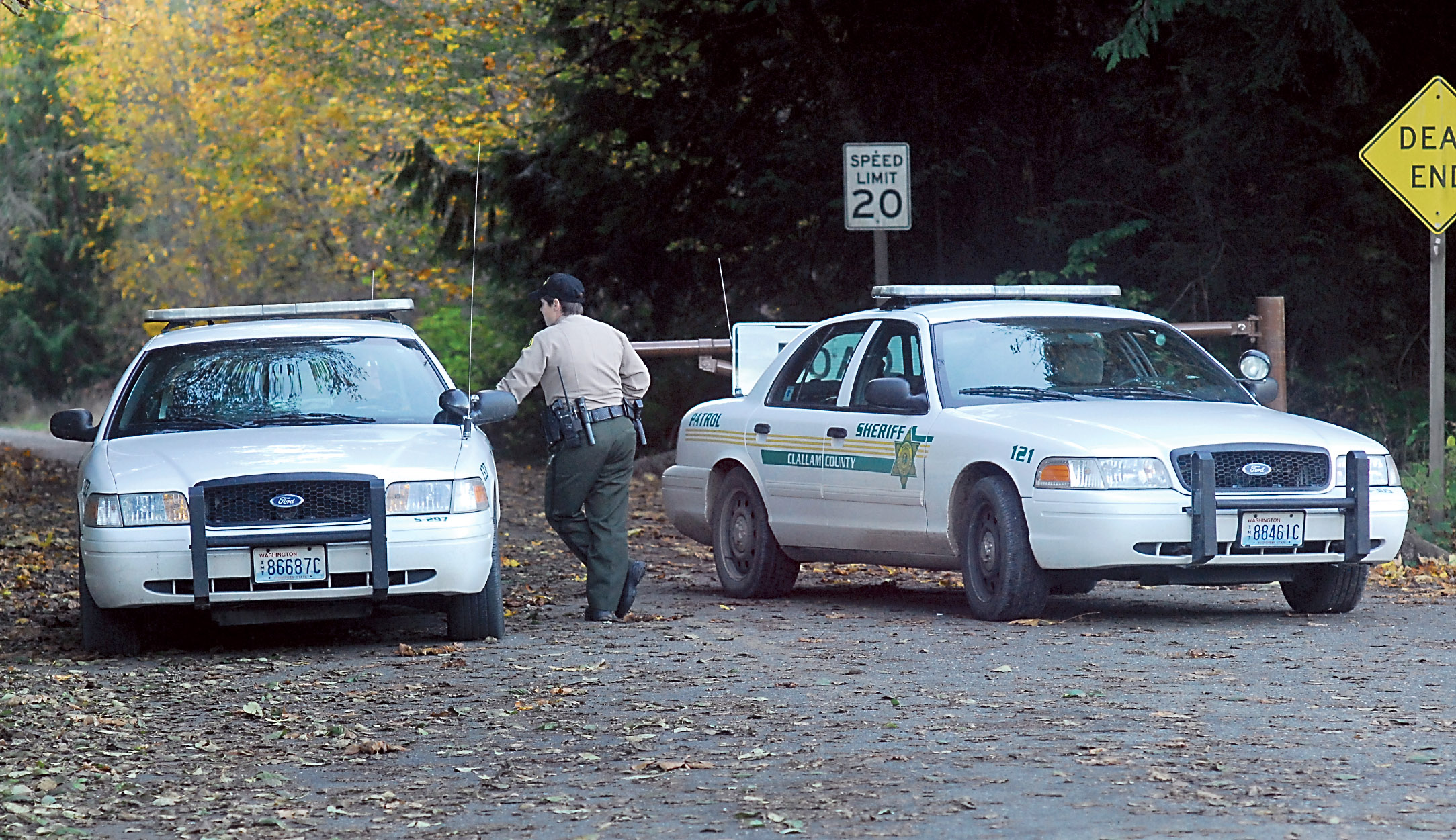 Clallam County Sheriff's Deputy Amy Bundy confers with another deputy while guarding the access to Lower Dam Road west of Port Angeles on Thursday after a body was found in the woods near the site of the former Elwha Dam. Keith Thorpe/Peninsula Daily News