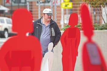 Life-size cutout figures surround Rod Shawver of Port Angeles at The Gateway transit center in Port Angeles in October 2011.  Each figure represents a victim of domestic violence. Chris Tucker/Peninsula Daily New