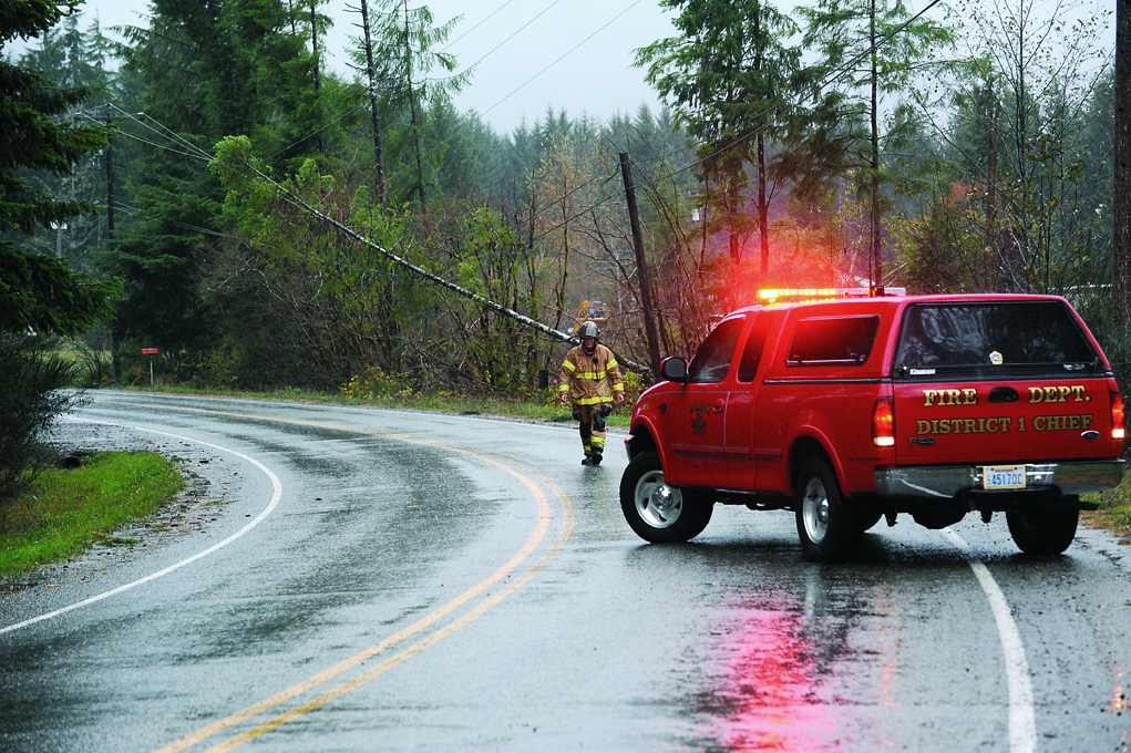 Forks Fire Chief Bill Paul of Fire District No. 1 blocks one lane of Merchant Road in Forks where a tree came across both power and telephone lines Saturday morning at about 9:05. Lonnie Archibald/for Peninsula Daily News