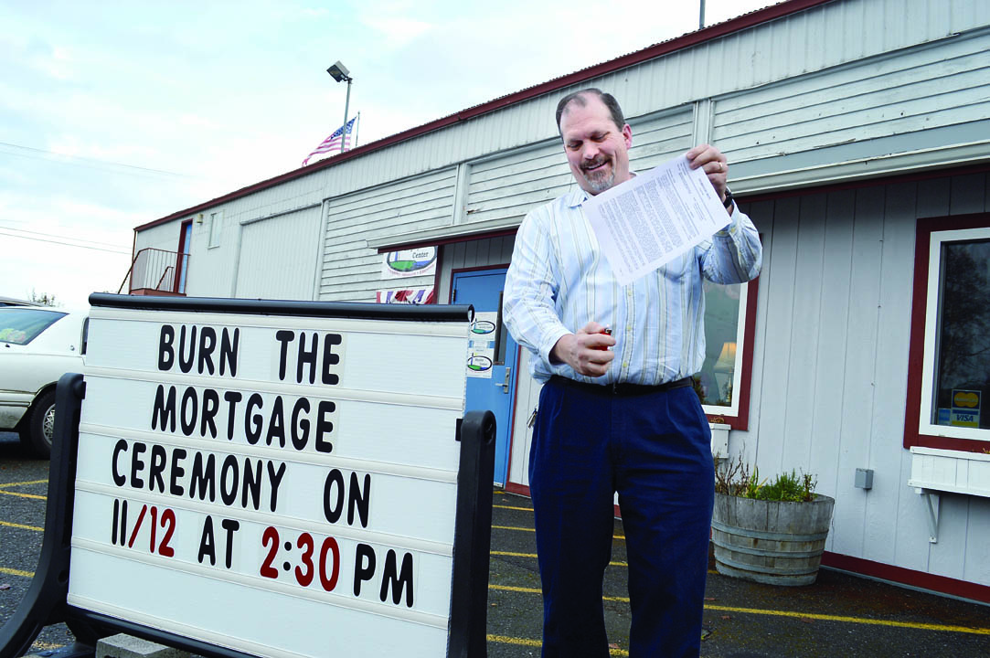 Shipley Center director Michael Smith holds a lighter to the center's mortgage to preview next Tuesday's ceremony officially retiring the debt. Joe Smillie/Peninsula Daily News