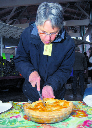 Port Angeles Farmers Market board member Patty Hannah slices a pie during the market's inaugural homemade apple pie contest on Saturday. Keith Thorpe/Peninsula Daily News