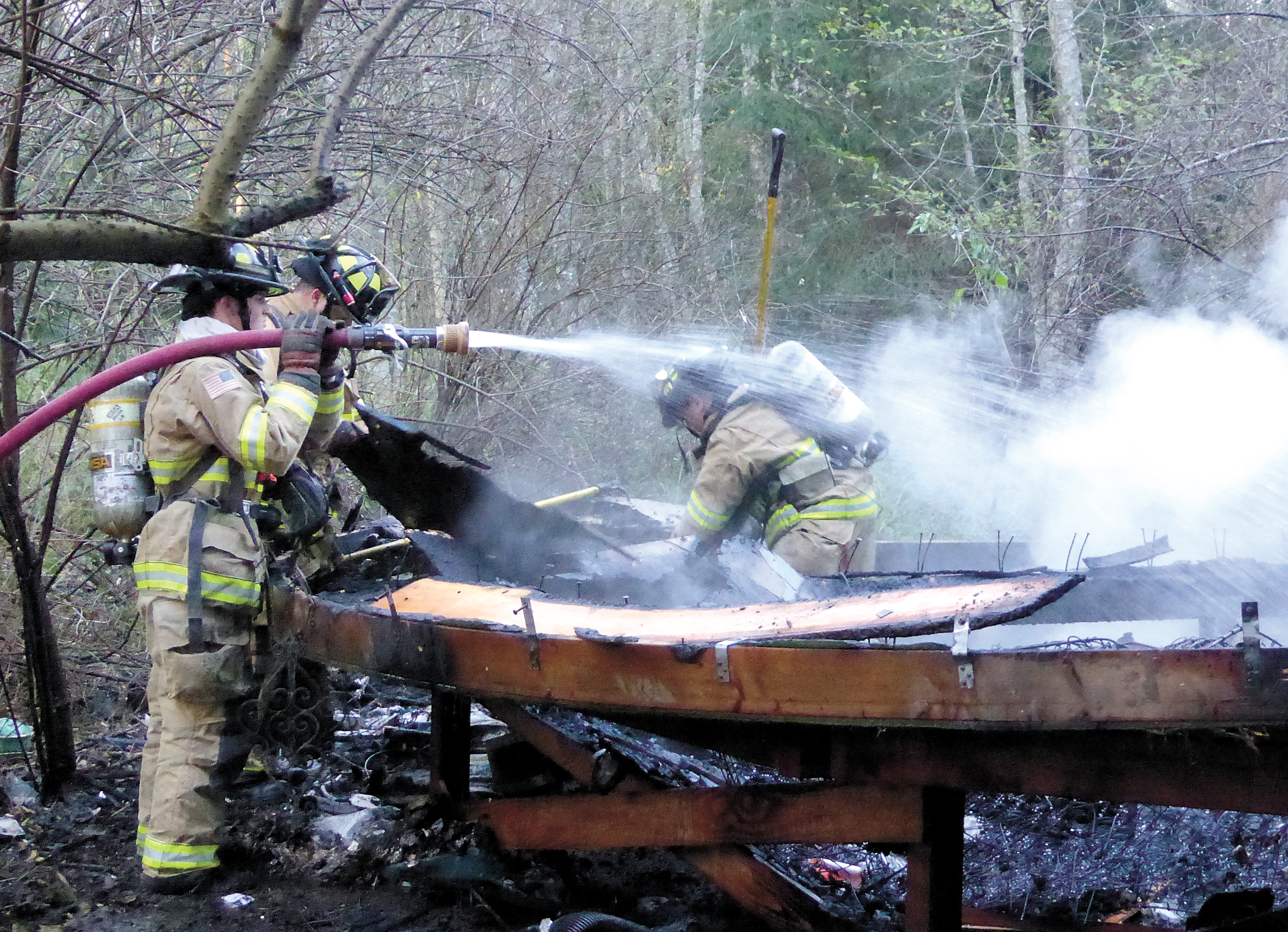 Firefighters put the final touches on extinguishing a blaze that leveled a yurt just south of Port Townsend on Thursday. Charlie Bermant/Peninsula Daily News