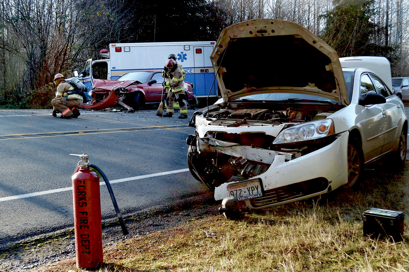 Fire District No. 1 crews sweep up U.S. Highway 101 after a head-on collision sent two to the hospital and closed the highway for a half-hour. Joe Smillie/Peninsula Daily News