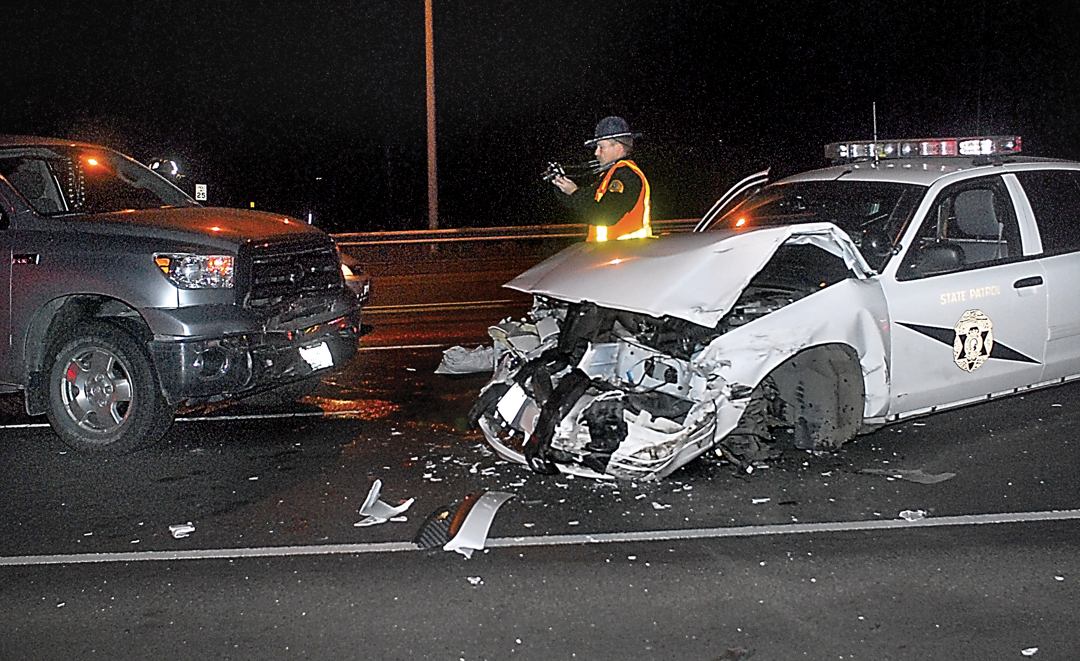 State Patrol Trooper Keith Nestor takes photos to document a collision involving a State Patrol cruiser and other vehicles Friday near Port Angeles. Keith Thorpe/Peninsula Daily News