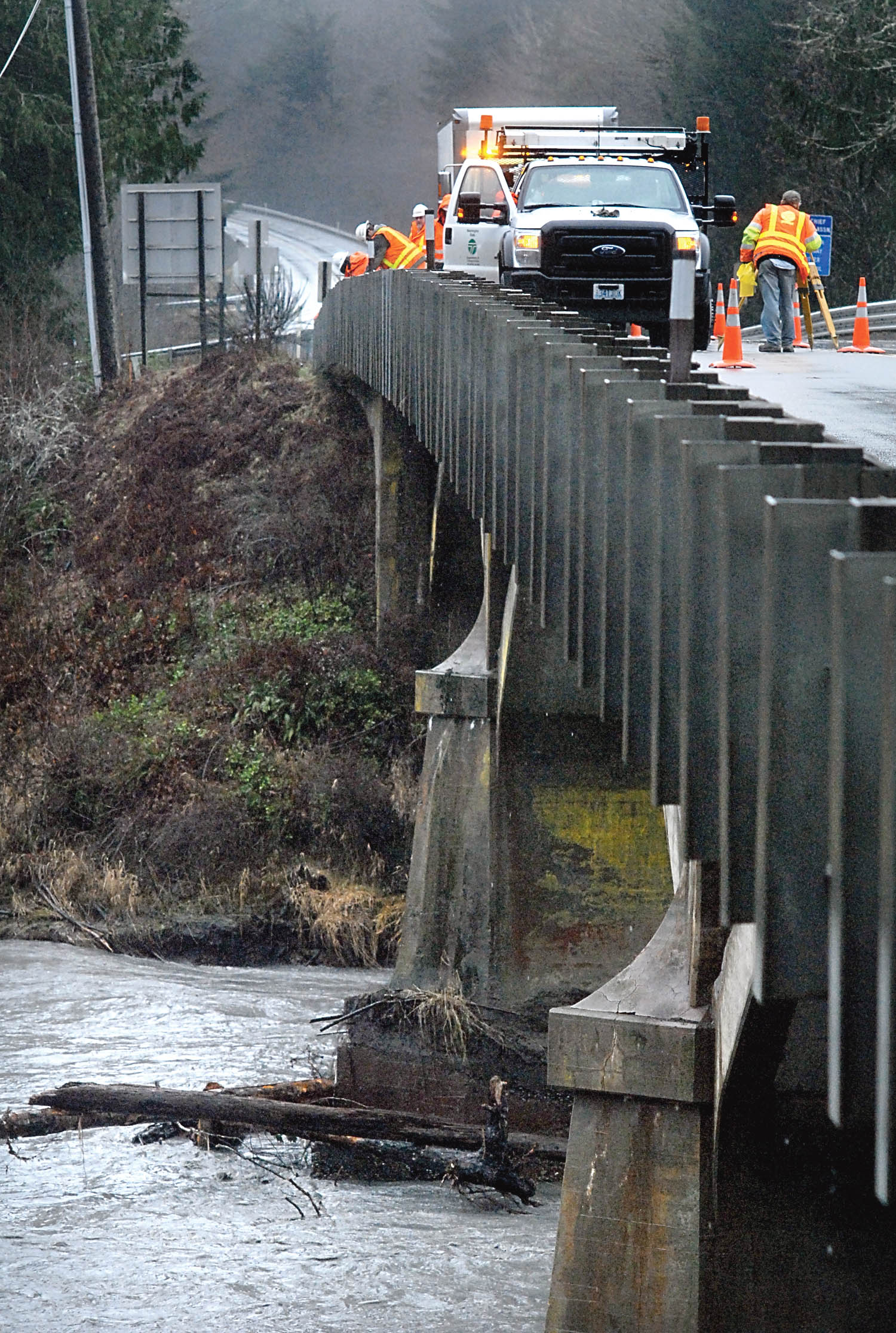 State Department of Transportation workers inspect the U.S. Highway 101 bridge over the Elwha River west of Port Angeles on Thursday after it was battered by high water and falling trees on Wednesday night. Keith Thorpe/Peninsula Daily News