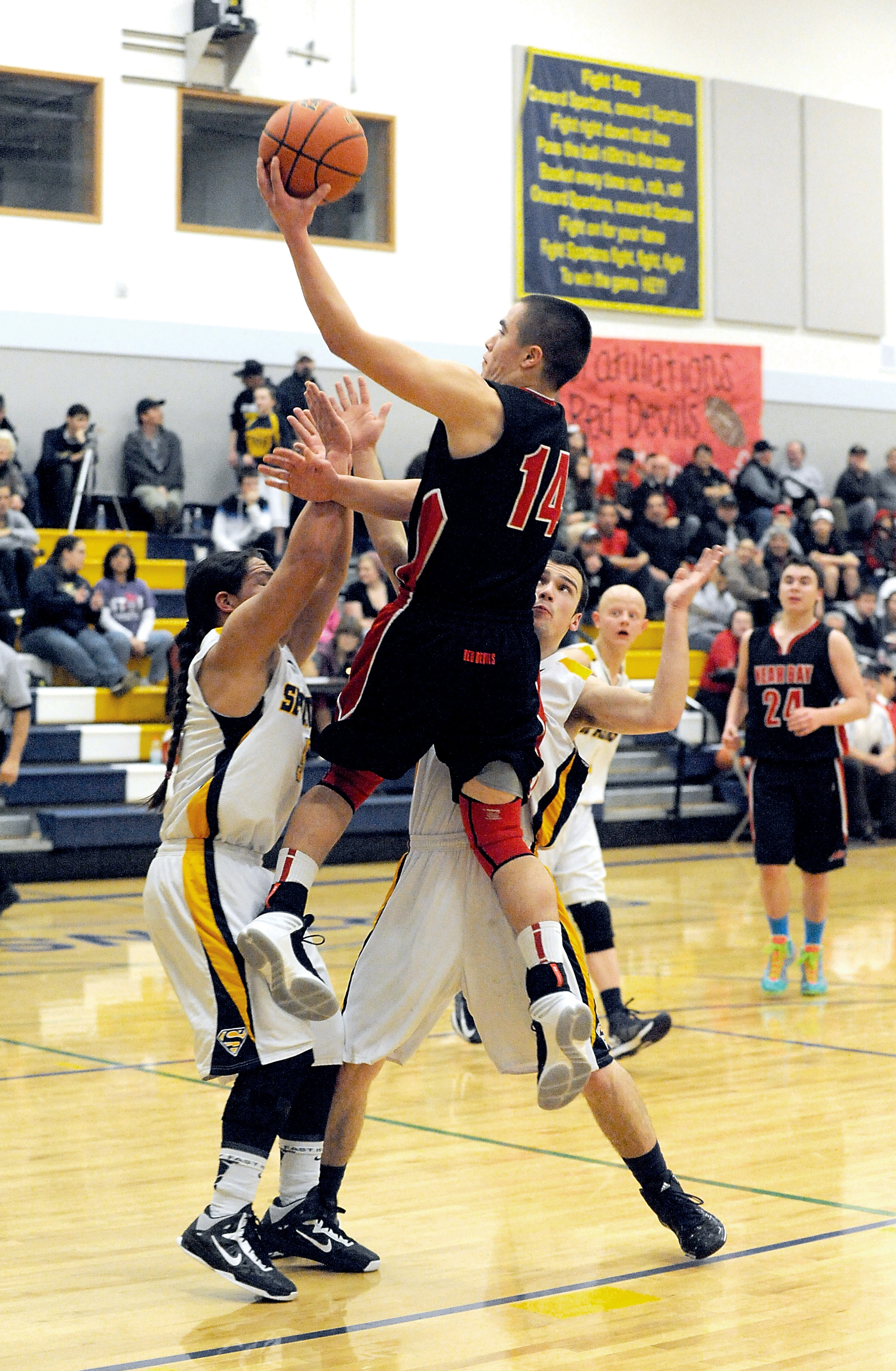 Neah Bay's Ezekiel Greene (14) drives for a lay up over Forks' Dimitri Sampson