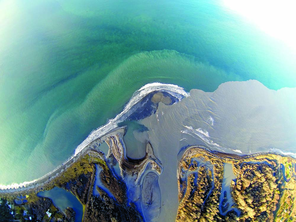 Waves break on sandbars at the mouth of the Elwha River on Dec. 18 as an aerial photograph shows sediment coming into the Strait of Juan de Fuca. Tom Roorda