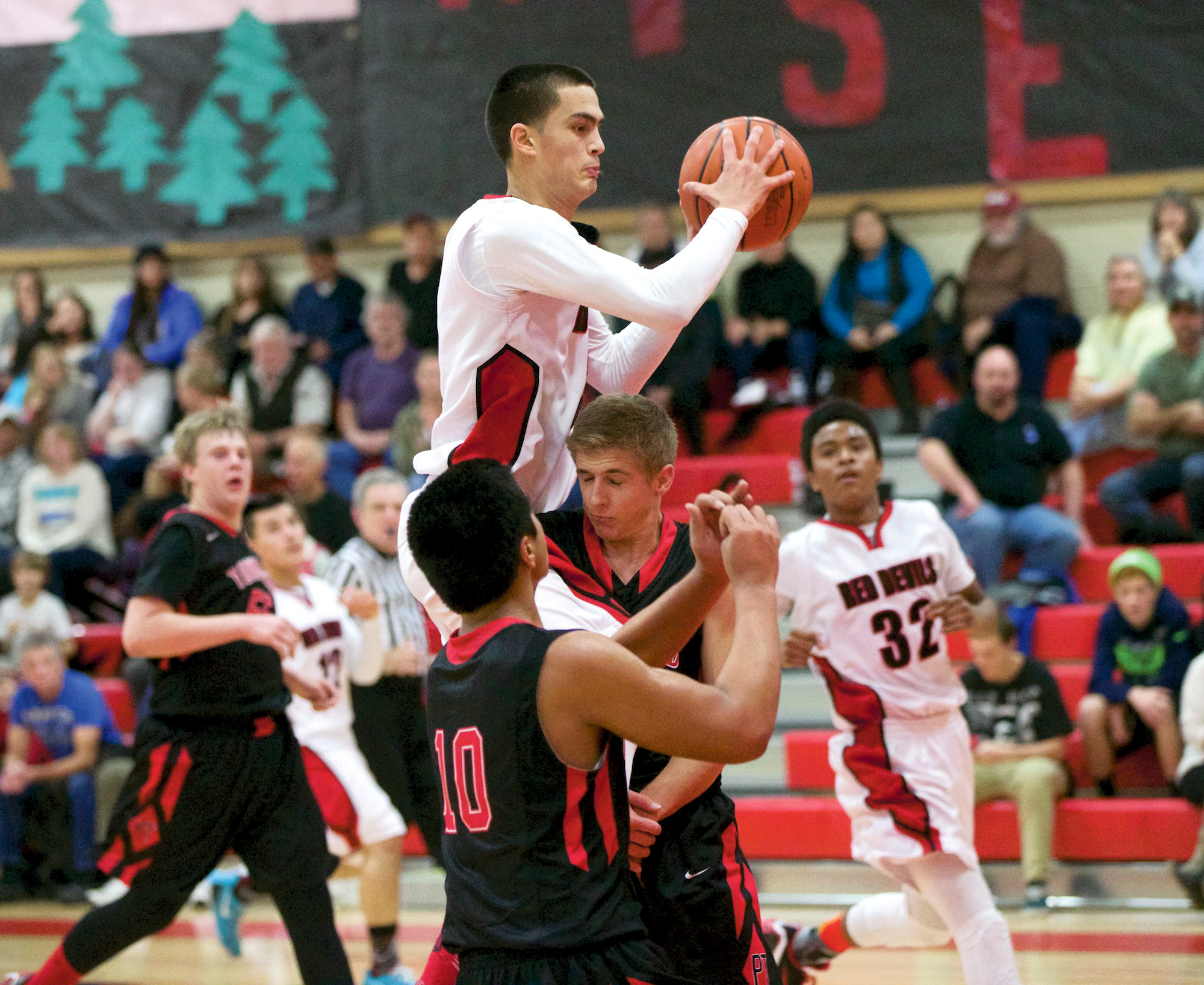 Neah Bay's Abraham Venske collides with Port Townsend's Jacob Ralls and Detrius Kelsall (10). Venske injured his hip on the play but returned to lead all scorers with 20 points in the Red Devils' 80-41 win. Steve Mullensky/for Peninsula Daily News