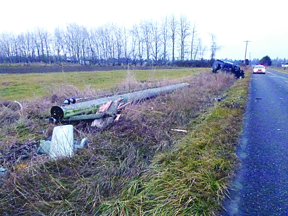 A Clallam County sheriff's deputy watches over a black Hummer SUV that knocked over a power utility pole on Woodcock Road west of Kitchen-Dick Road near Sequim on New Year's morning around 7 a.m.