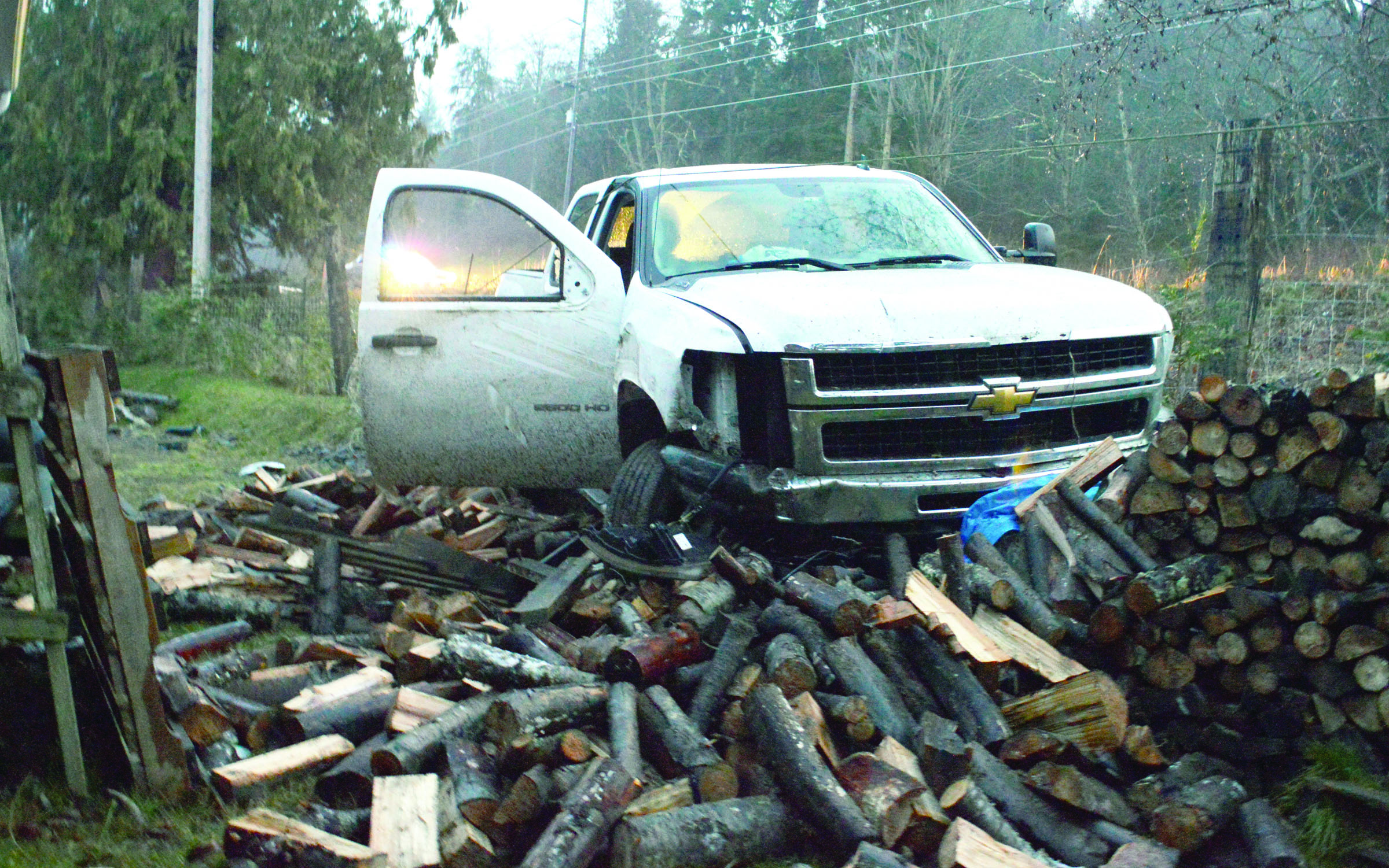 Hugh Haffner’s pickup truck rests at the woodpile it crashed into this afternoon. The Clallam County Public Utility District commissioner was taken to a hospital.  -- Photo by Joe Smillie/Peninsula Daily News