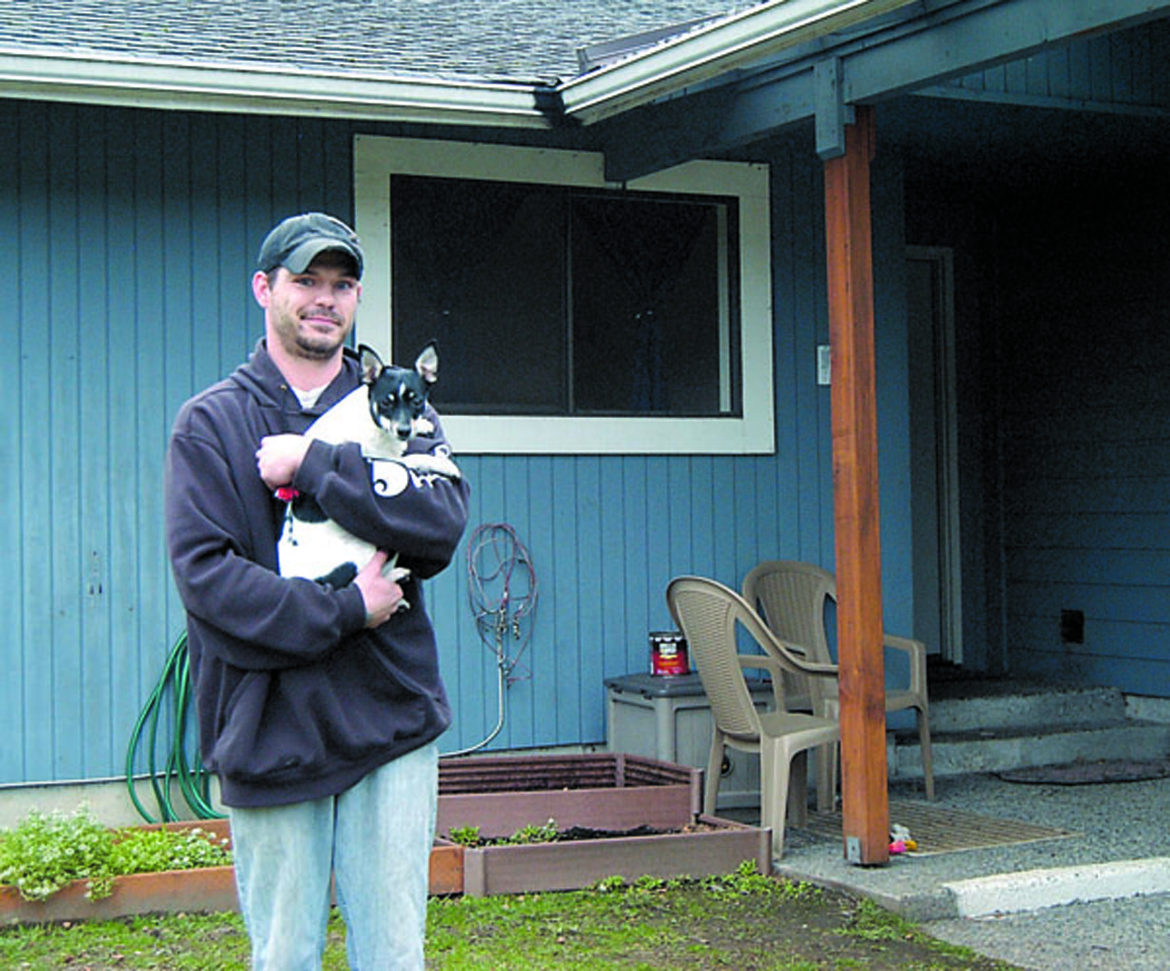 Clint Lowery stands in front of his home in west Port Angeles with his dog