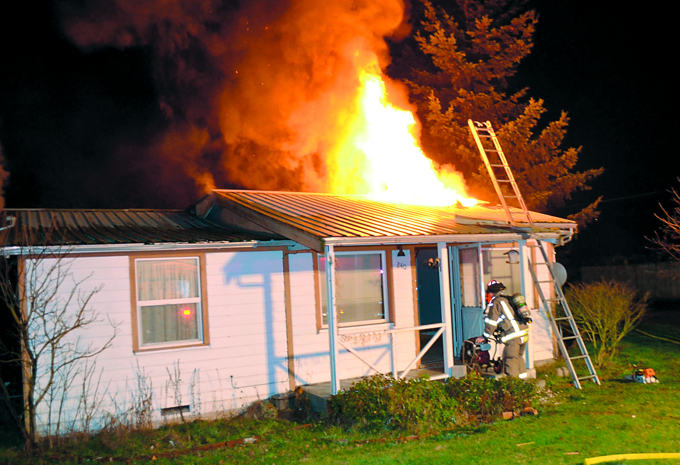 Fire Capt. Chris Turner places a fan at the entrance of a burning house on South Fifth Avenue in Sequim.  -- Photo by Patrick Young/Clallam County Fire District No. 3