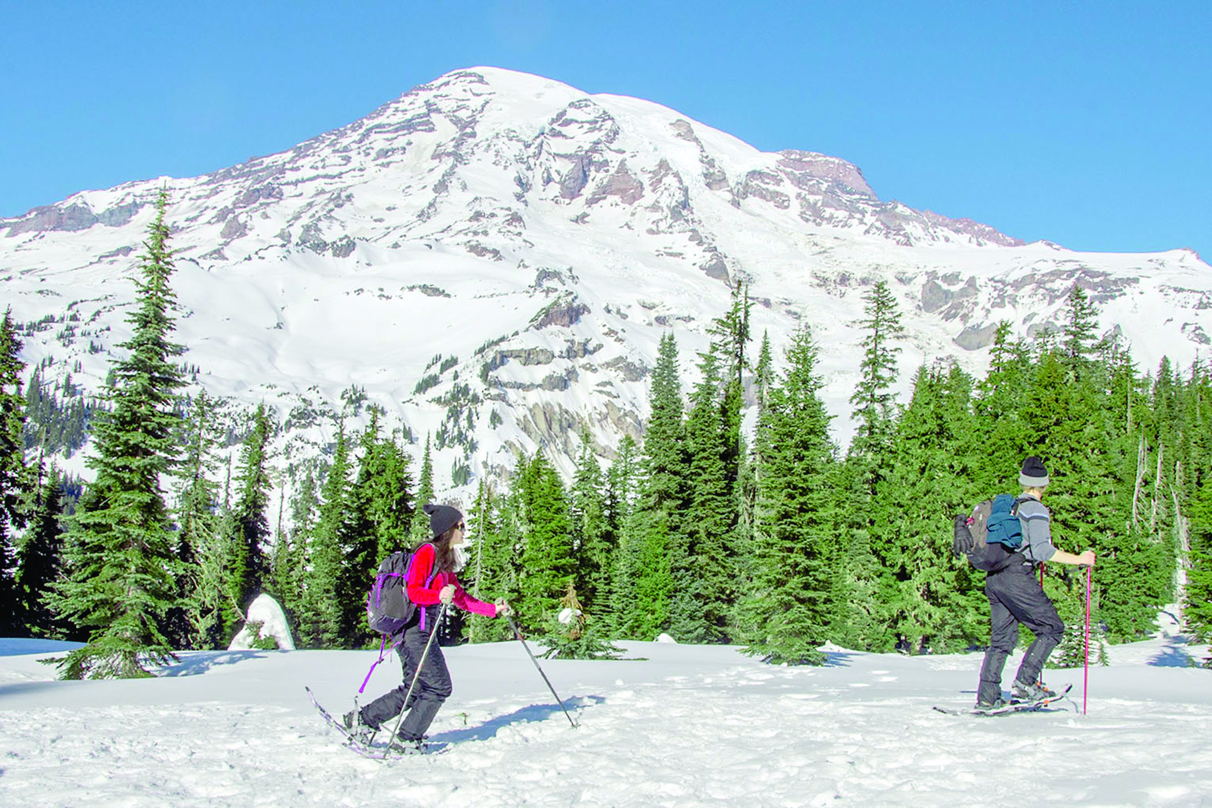 People snowshoe near Paradise in view of Mount Rainier in January. State officials are monitoring lower than usual snowpack levels this winter. — The Associated Press