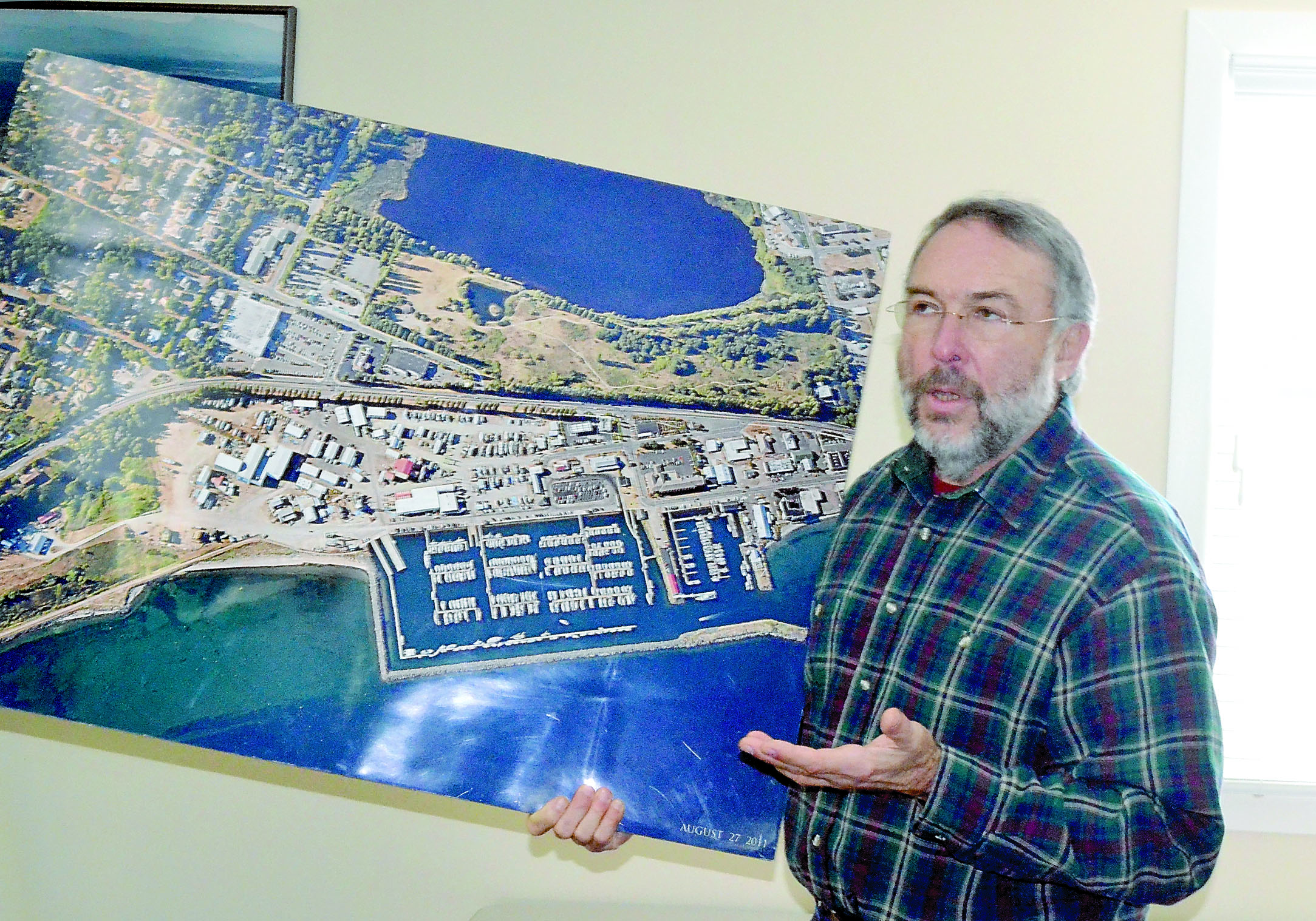 Port of Port Townsend Commissioner Steve Tucker holds an aerial shot of the Boat Haven during a meeting Wednesday. Closing a lane along the water will free up several parking spaces that will be able to accommodate peak season overflow. — Charlie Bermant/Peninsula Daily News