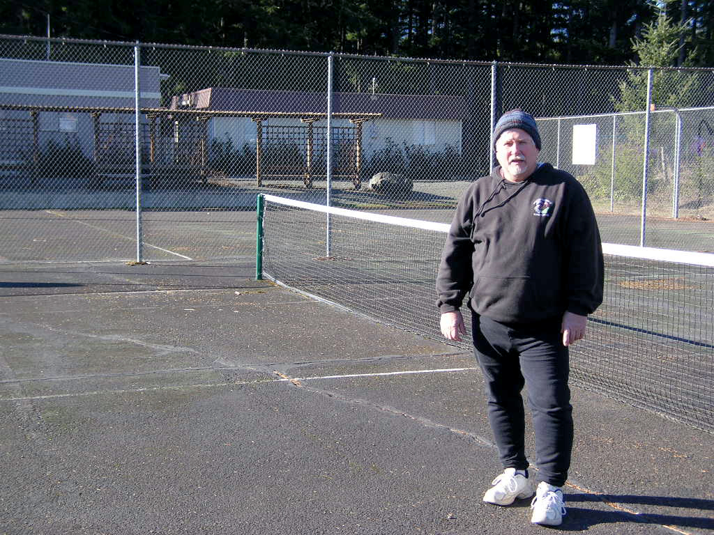 Clayton White stands on the basketball/tennis court in Quilcene that he hopes to see resurfaced.