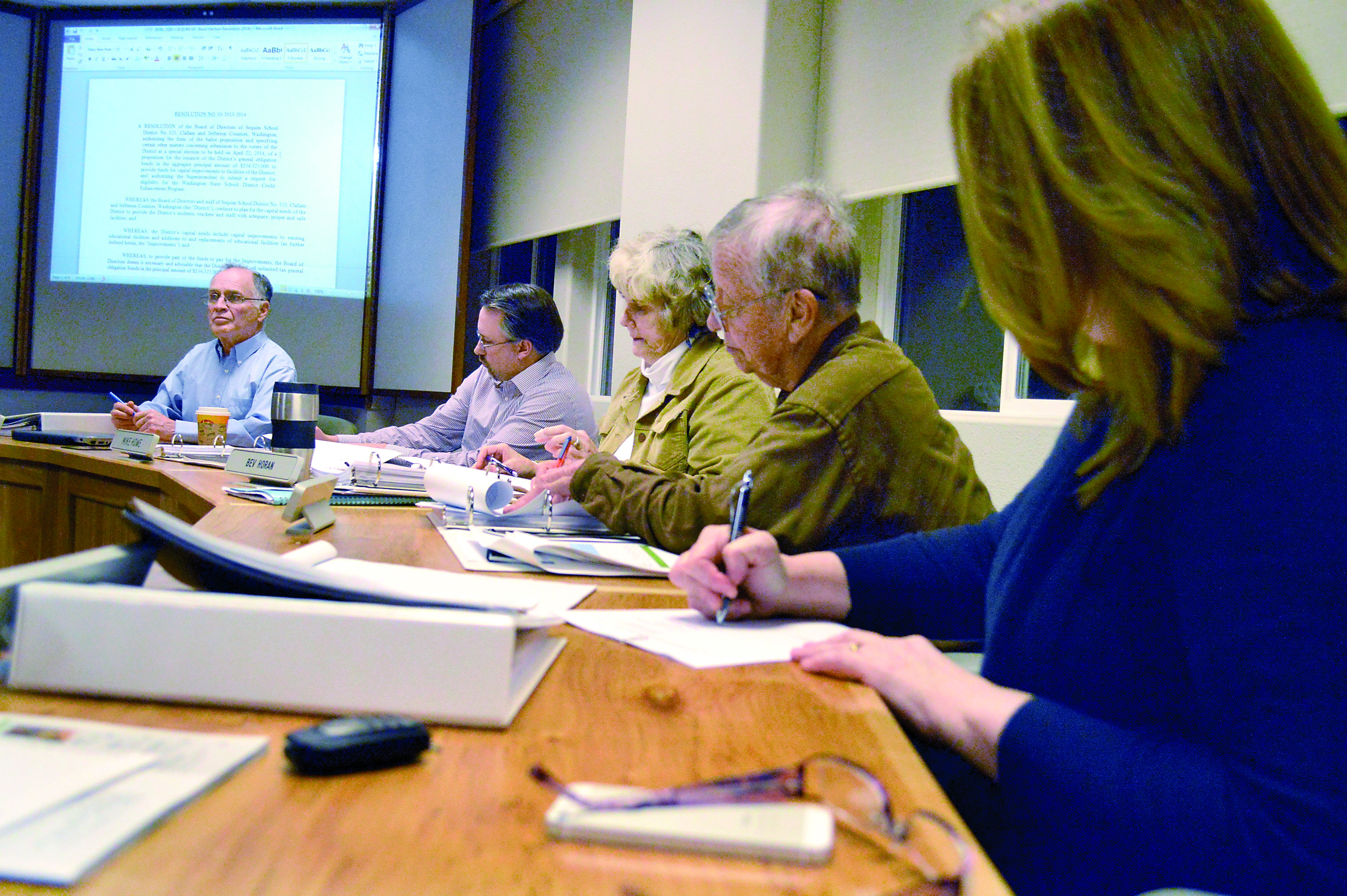 Sequim School Board members sign a resolution at Tuesday night’s board meeting to put a construction bond measure on the April 22 ballot. From left are President John Bridge