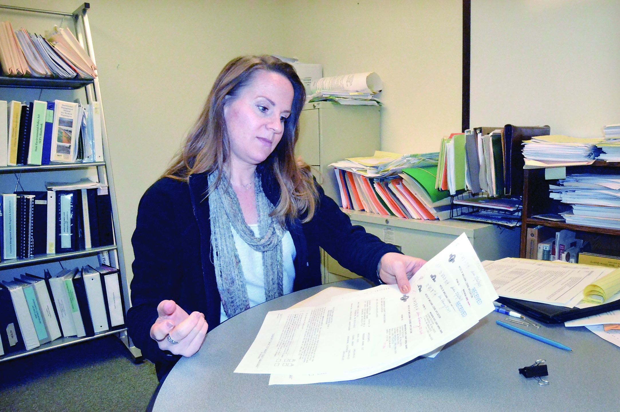 Jefferson County Planning Director Stacie Hoskins inspects some of the applications for marijuana operations in the unincorporated parts of the county.  —Photo by Charlie Bermant/Peninsula Daily News