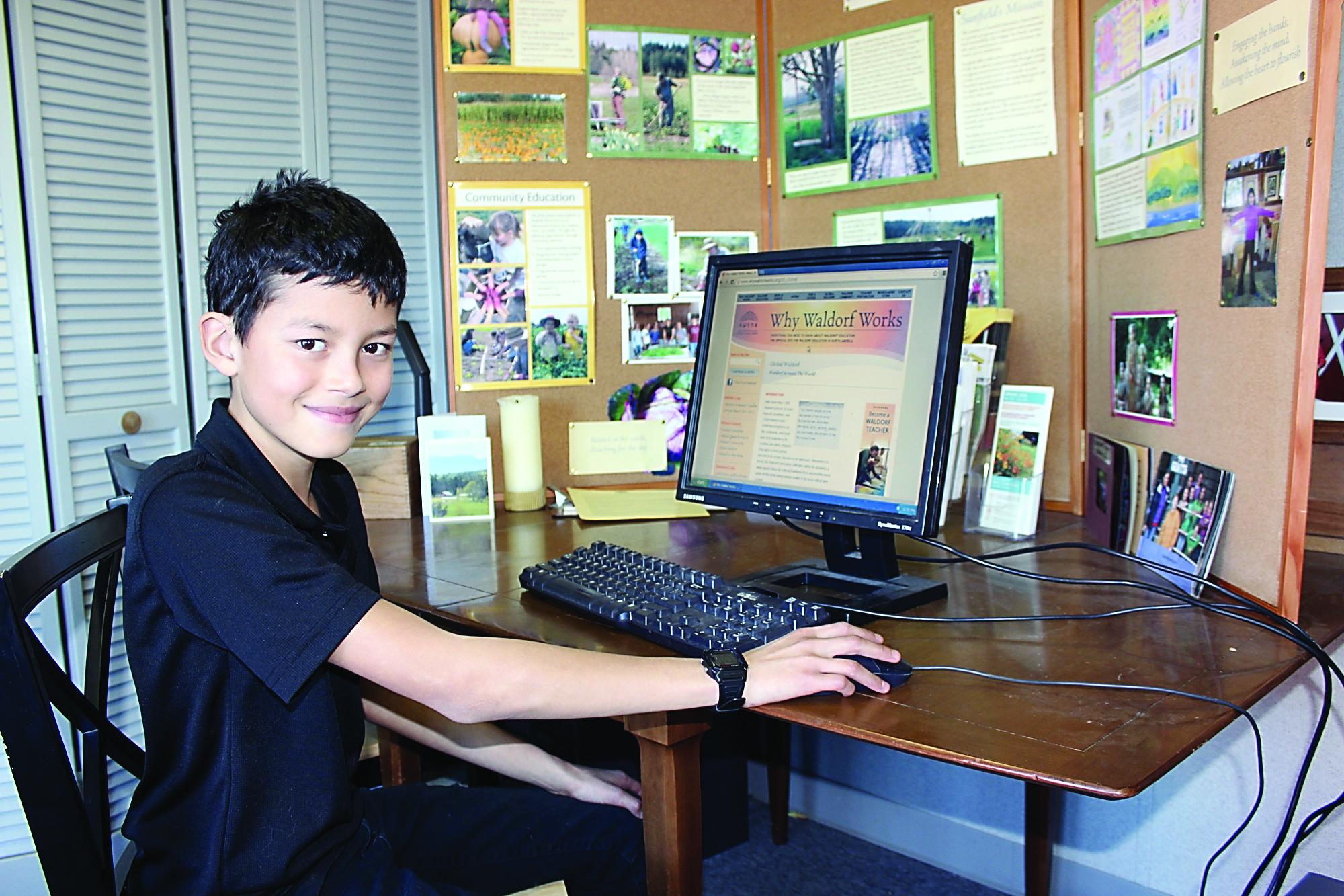 Sunfield fifth-grader Henry Van Loon sits in the Sunfield office lobby at the school computer donated by Intellicheck Mobilisa to the Sunfield Farm & Waldorf School.