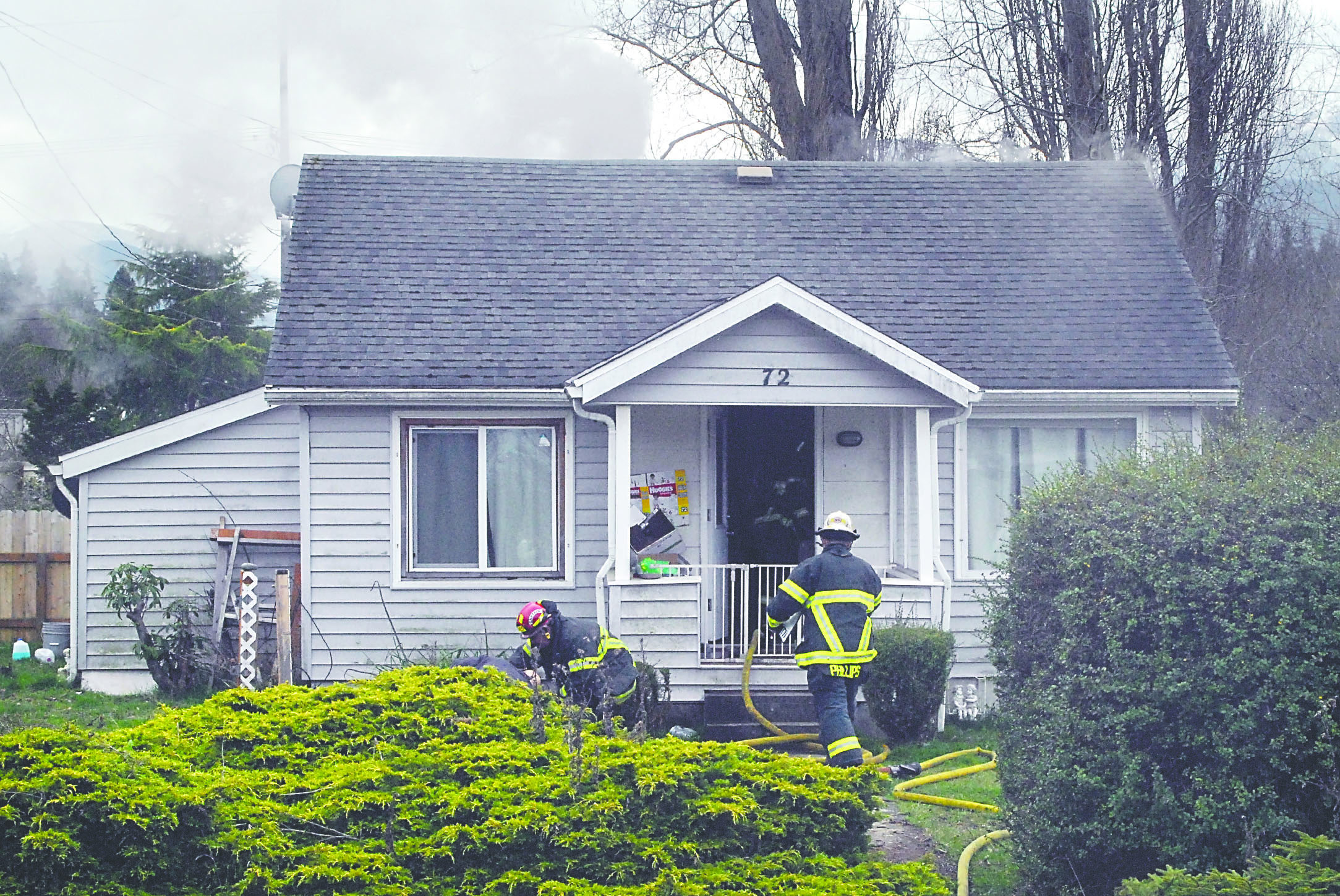 Clallam County Fire District No. 2 firefighters enter a house at 72 McCarver St. east of Port Angeles on Tuesday as smoke pours from the attic of the house. Keith Thorpe/Peninsula Daily News