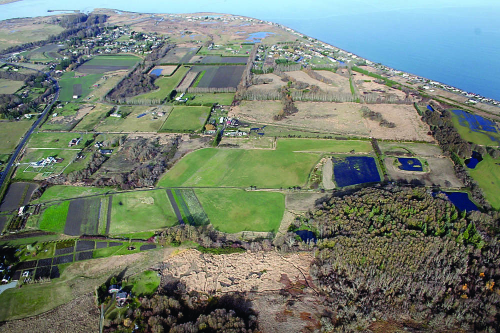 An aerial photograph shows the permanently conserved farmland and wildlife habitat on private properties near the mouth of the Dungeness River. About 325 acres of farmland and habitat in this photo are permanently conserved through conservation easements between the North Olympic Land Trust and local landowners. Russ Melon