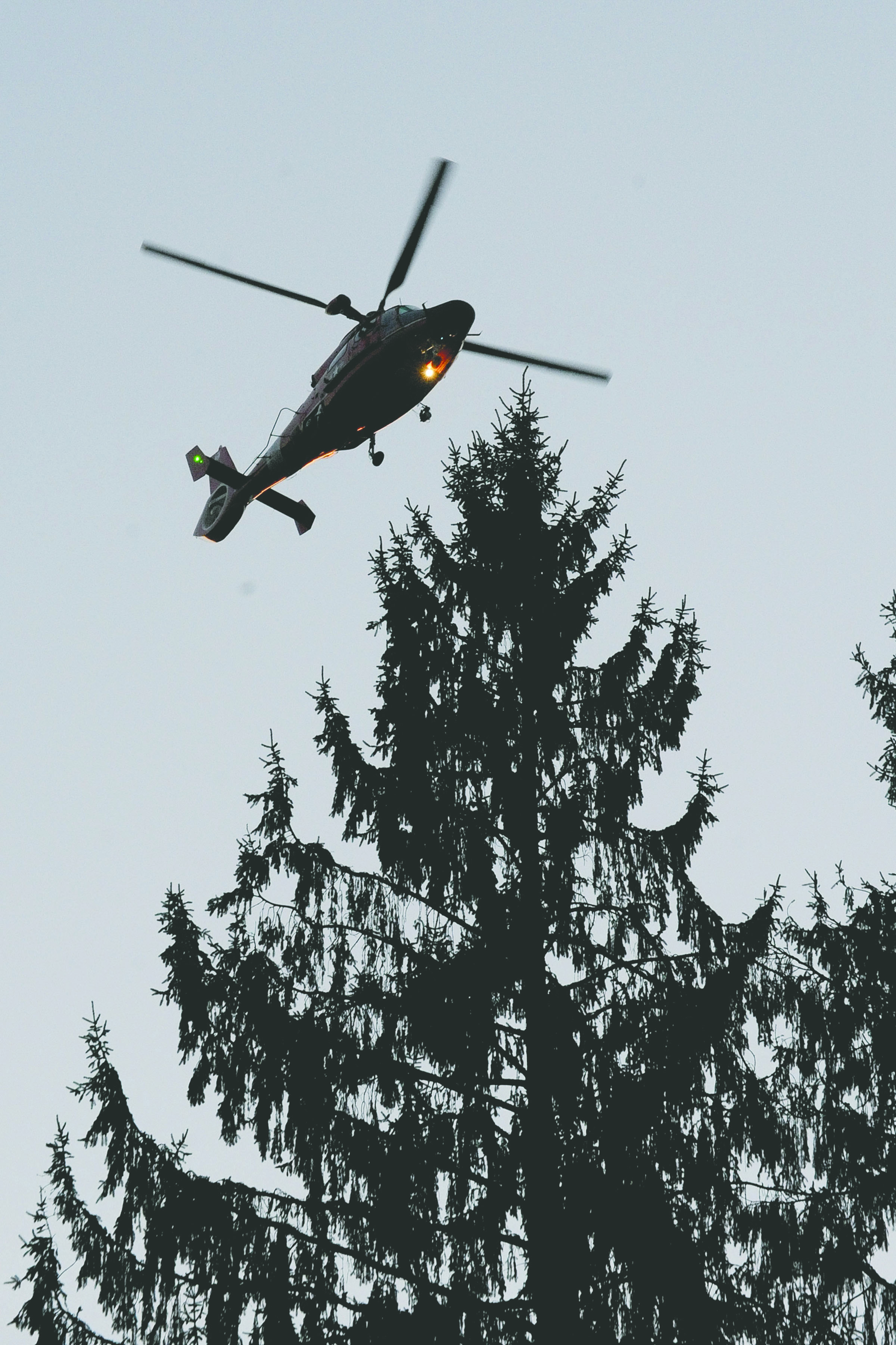 A Coast Guard helicopter from Air Station/Sector Field Office Port Angeles searches along the Bogachiel River before dusk Saturday.  —Photo by Lonnie Archibald/for Peninsula Daily News