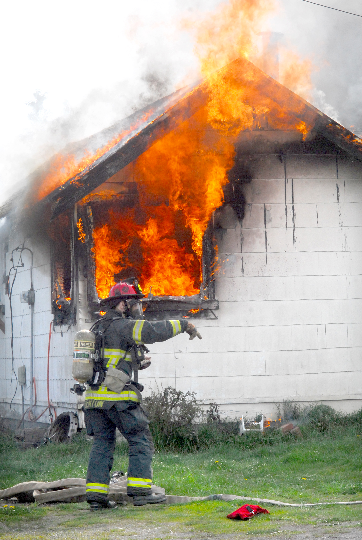 Port Angeles firefighter Kevin Denton prepares to take on a fire that destroyed a house at 4017 W. Fairmount Ave. in Port Angeles today. —Photo by Keith Thorpe/Peninsula Daily News