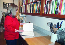 Nancy Machette looks for a recipe from her cookbook collection in a large pantry that includes a baking station with a farm sink